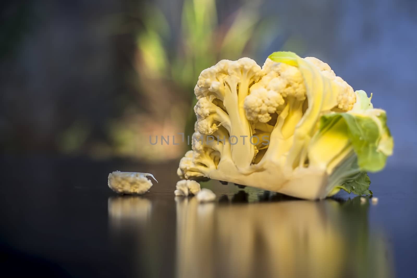 Close up shot of raw cauliflower on a black surface with selective focus, creative lighting, and blurred background.