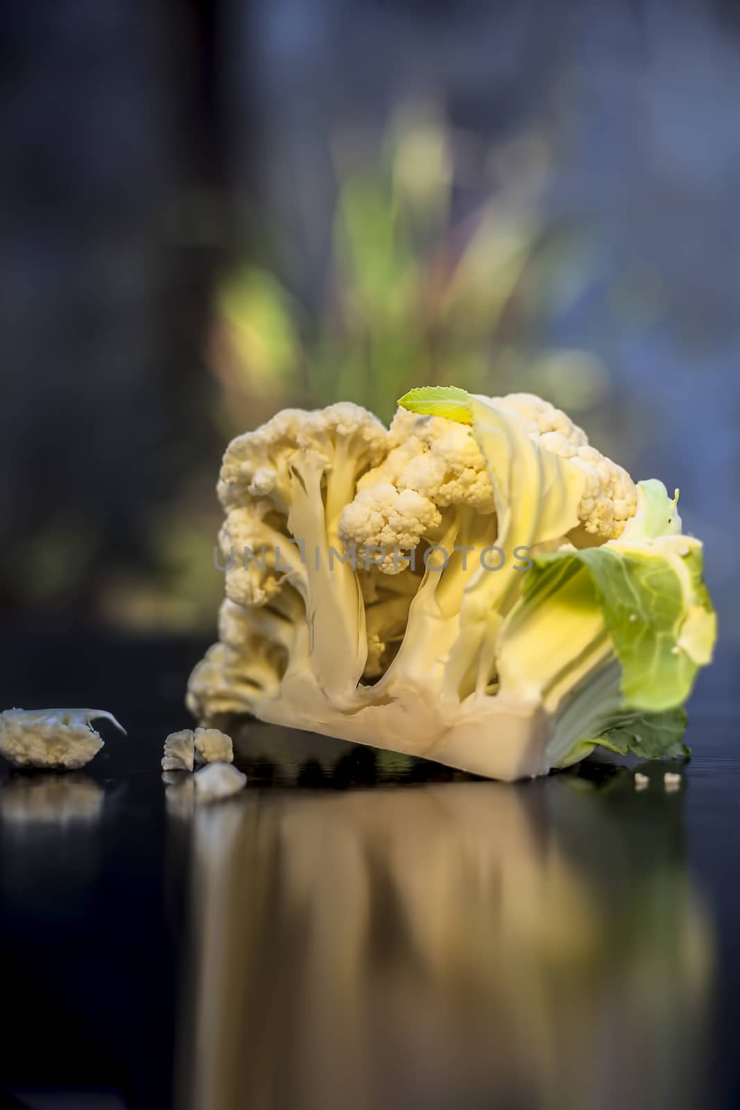 Close up shot of raw cauliflower on a black surface with selective focus, creative lighting, and blurred background. by mirzamlk