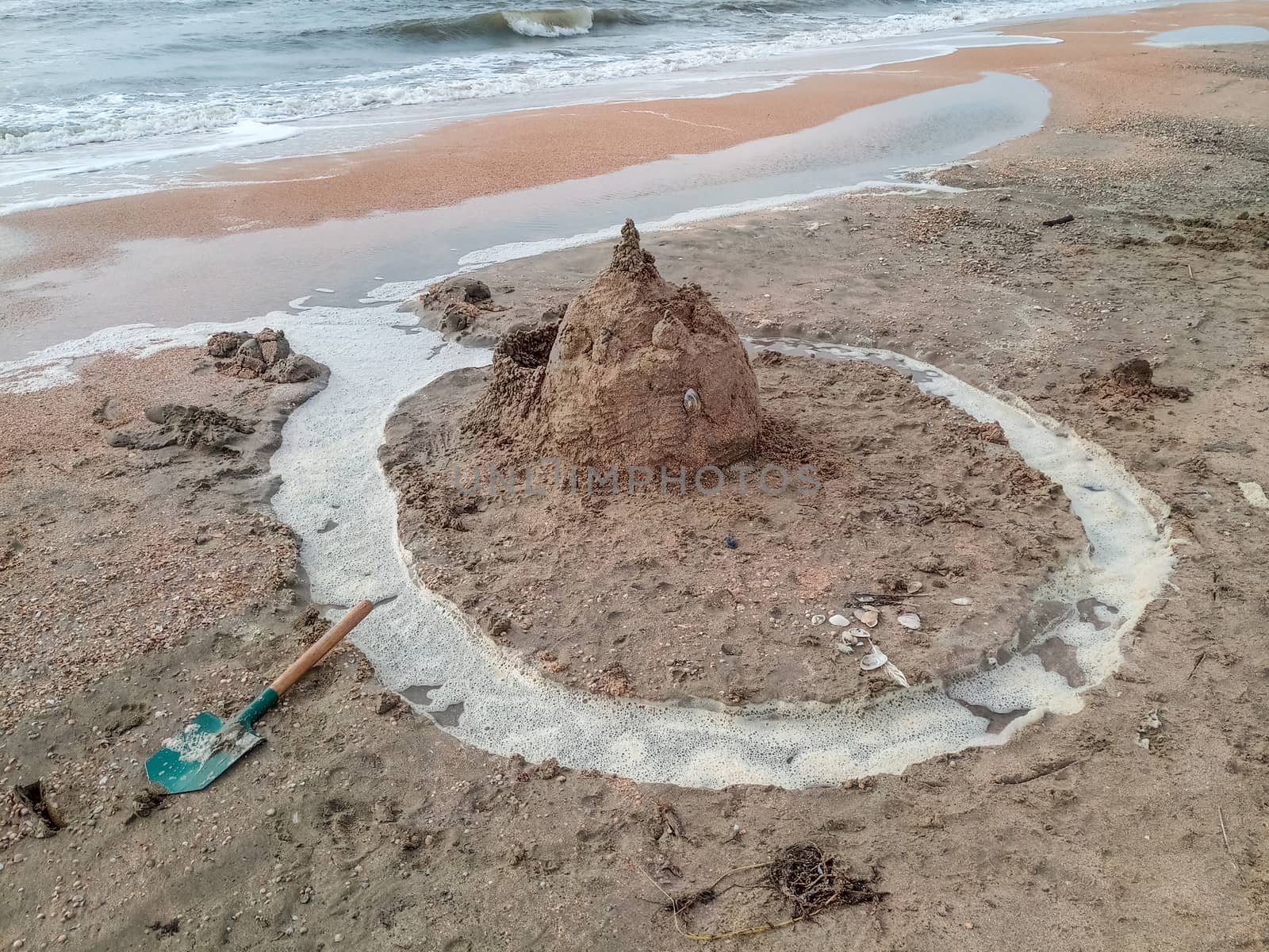 Sand castle on the beach with shells. Children's games at sea.