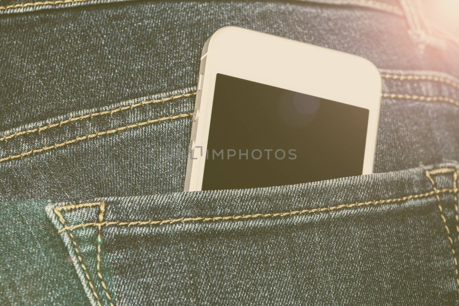 Girl on the street with a white generic smartphone in the rear pockets of jeans in vintage style