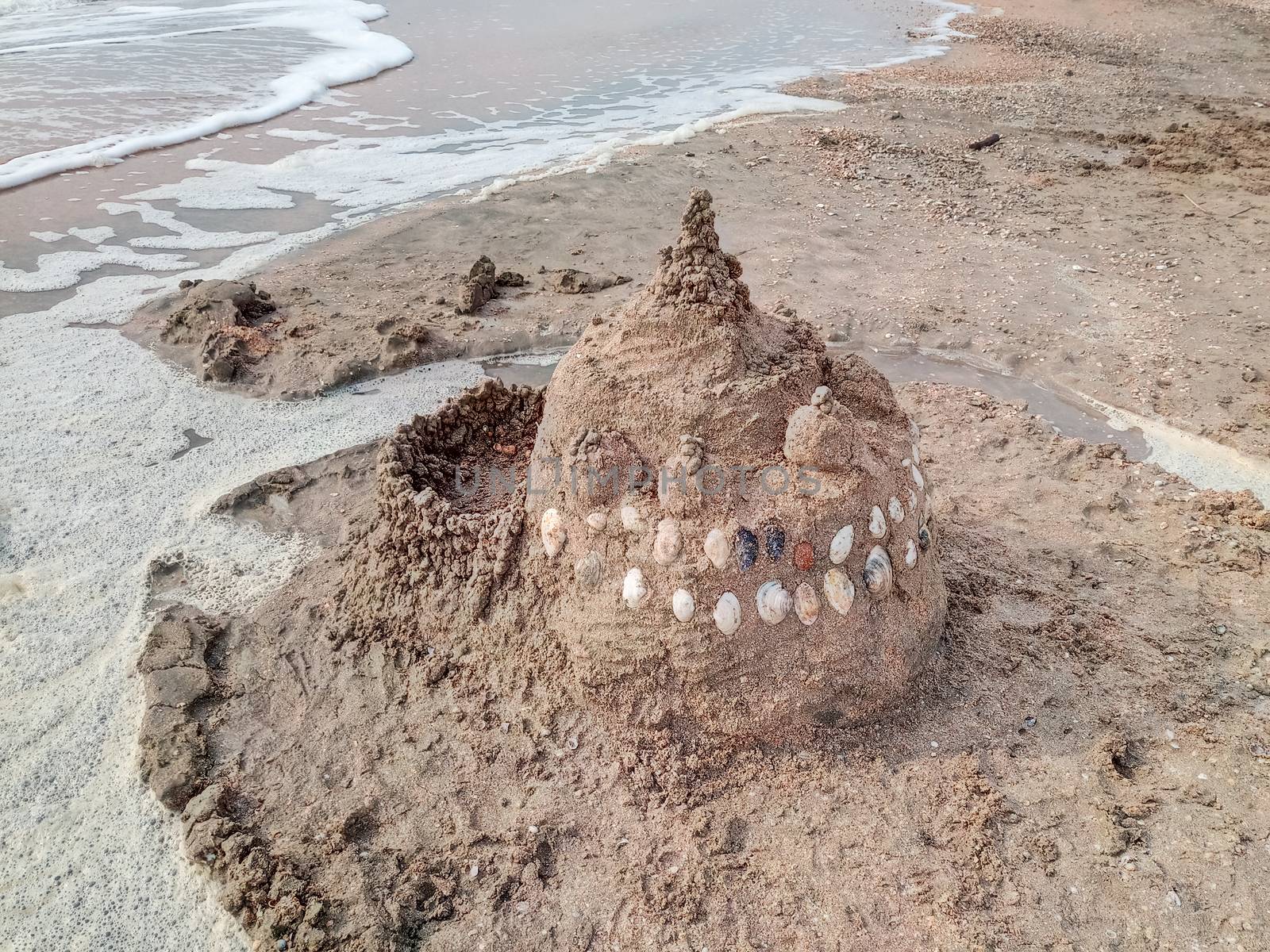 Sand castle on the beach with shells. Children's games at sea.