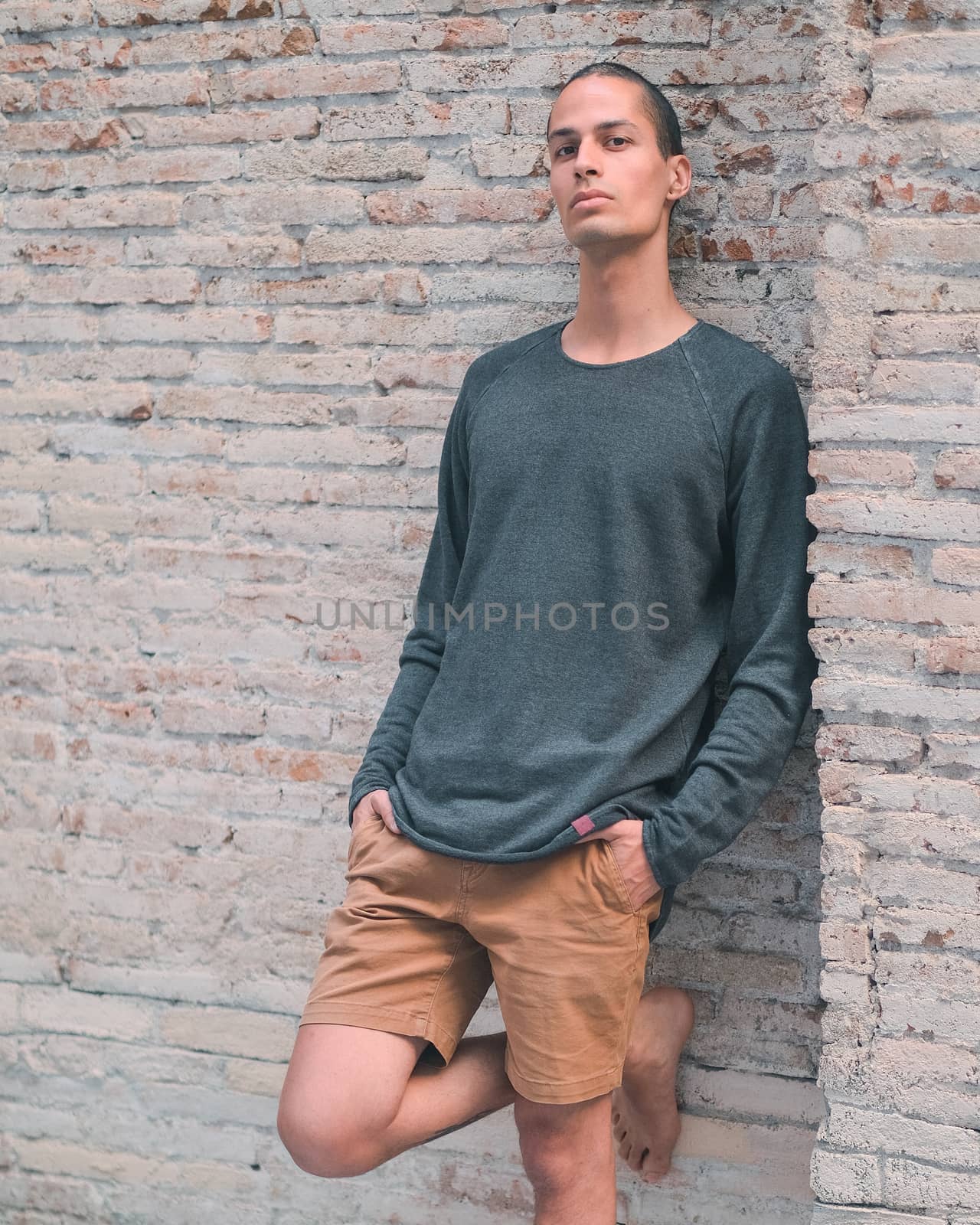 Exotic caucasian young man posing in front of a brick wall by Dumblinfilms