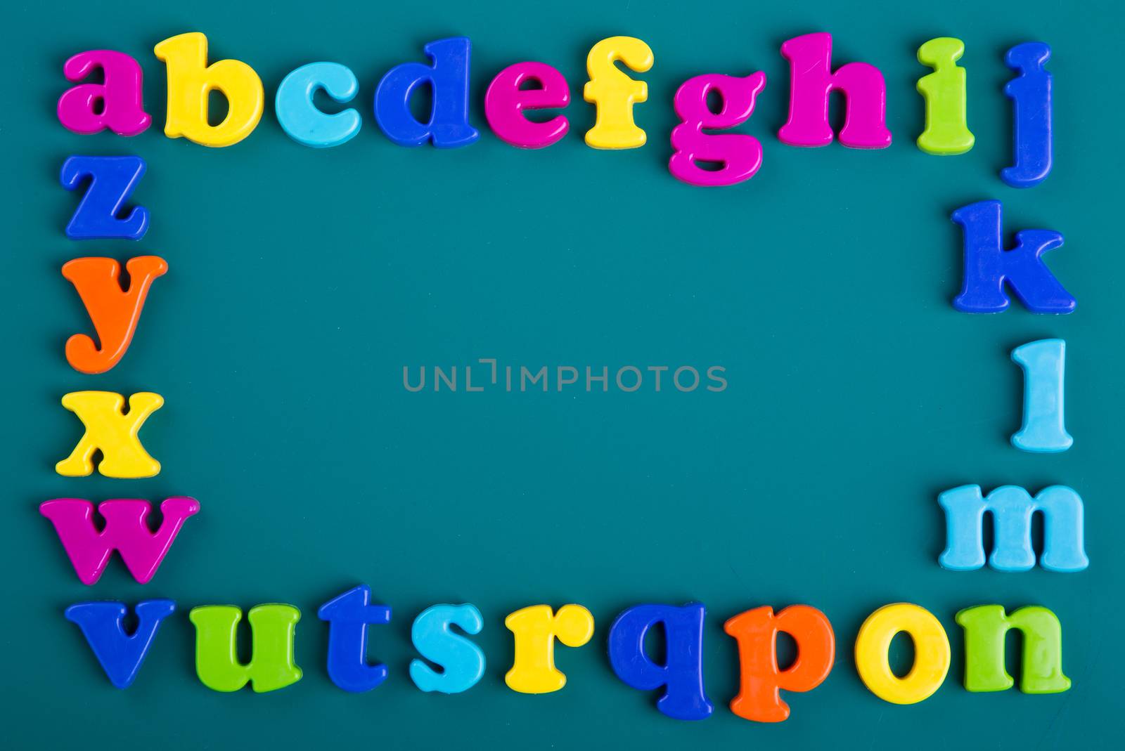 Frame of Colorful alphabet magnets on green background