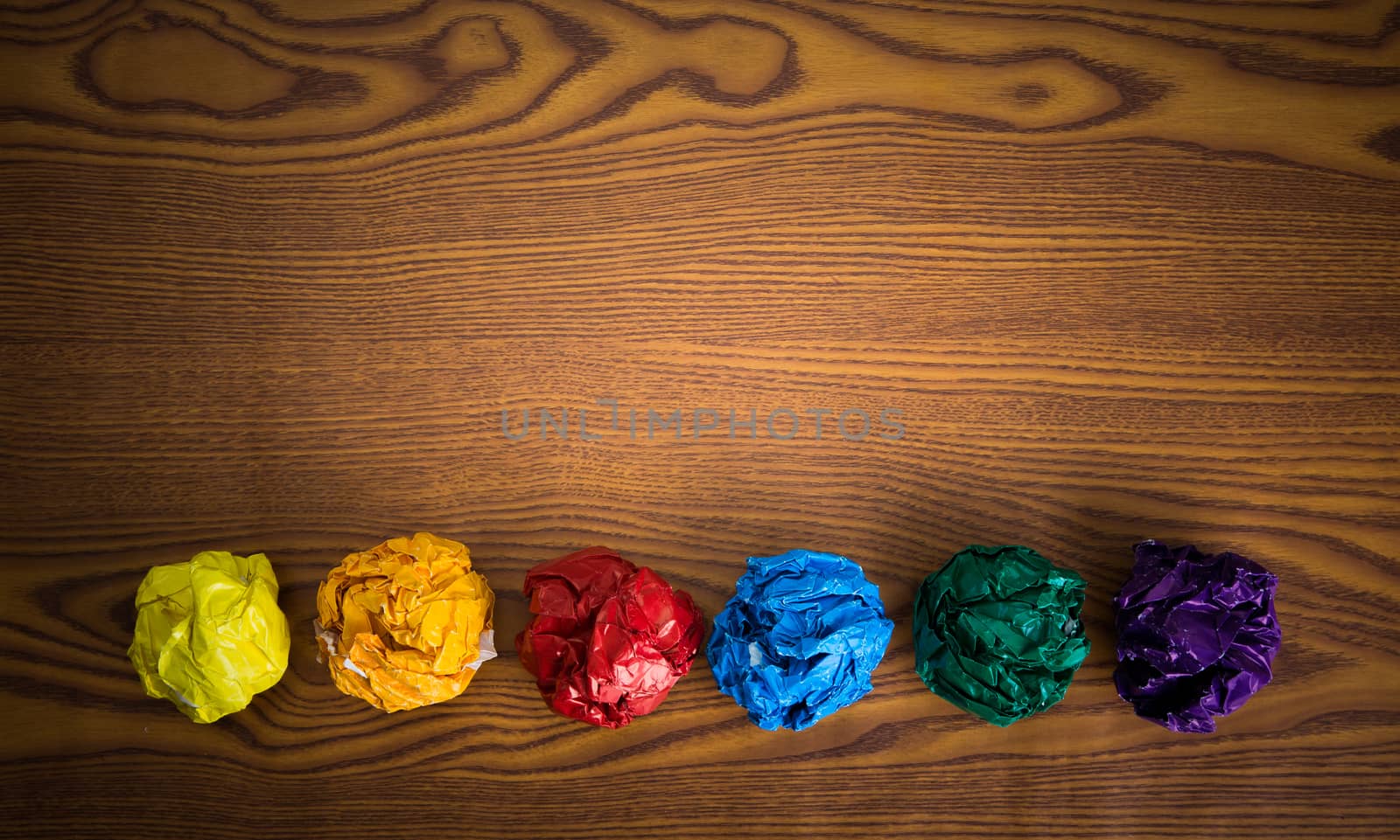 crumpled colorful paper on wooden background