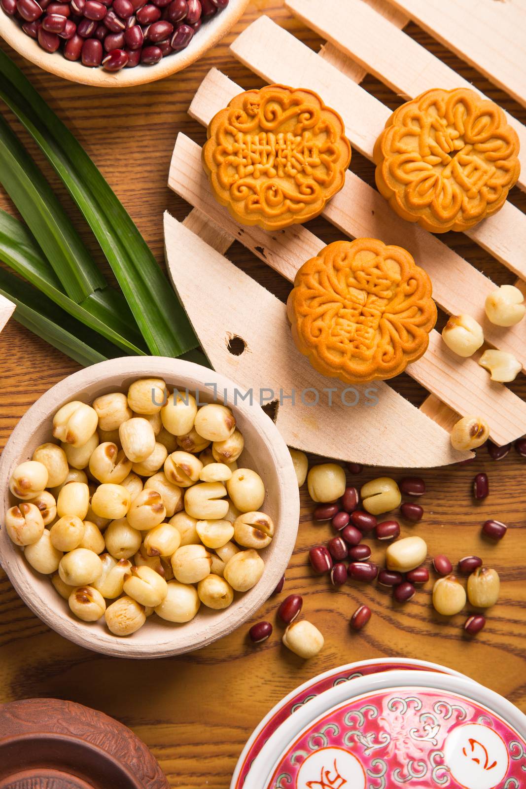 Traditional mooncakes on table setting with ingredients and teapot. Translation for those chinese words is red bean, lotus paste and jade paste.