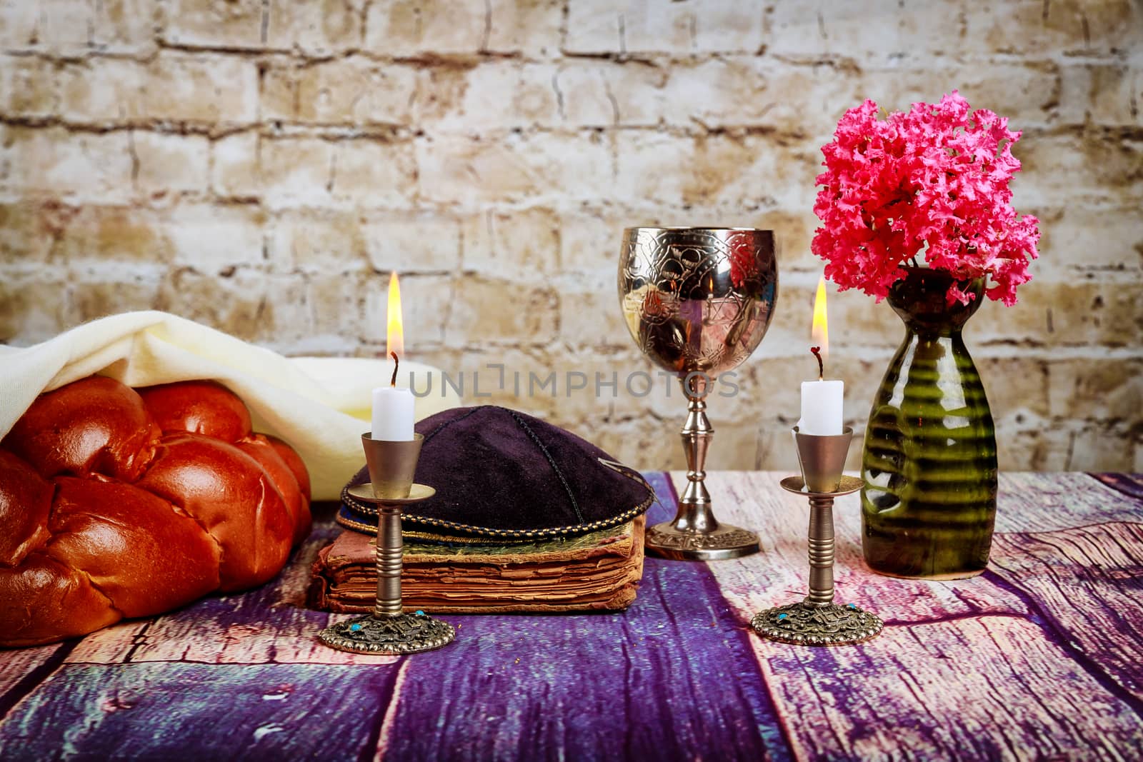 Shabbat candles in candlesticks of loaves challah for Shabbat wine in a cup with flowers