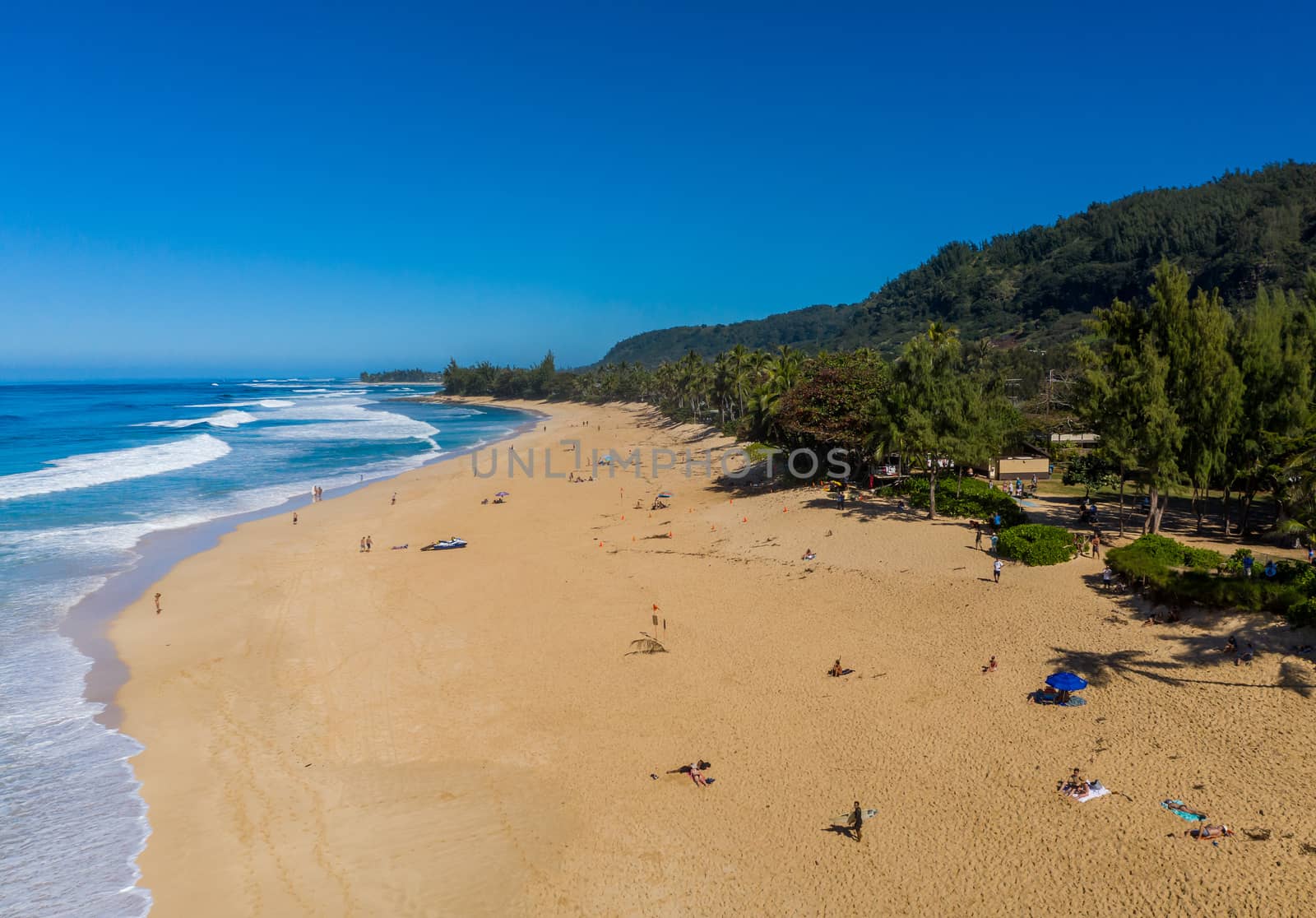 Locals and tourists on the sand beach at Banzai Pipeline on north coast of Oahu, Hawaii