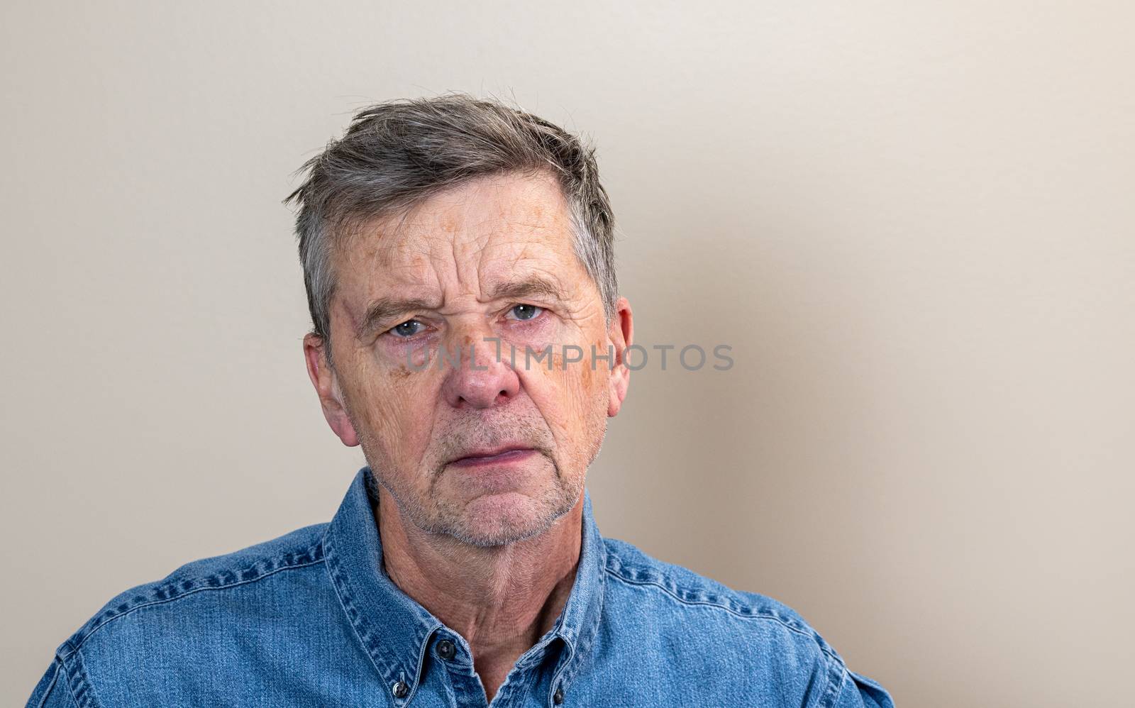 Head and shoulders portrait of a senior caucasian man unshaven and facing camera