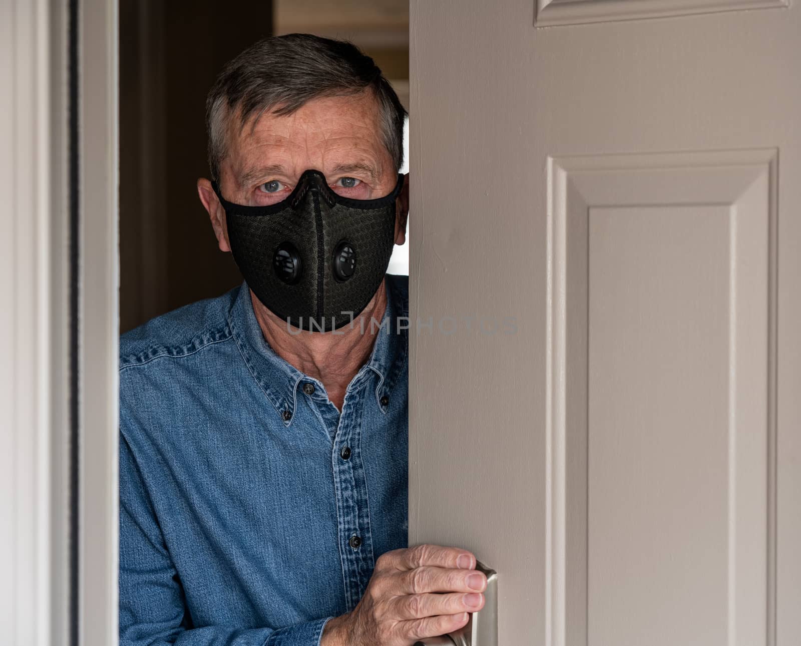 Concerned and worried man wearing a protective breathing mask against flu and coronavirus and greeting visitor