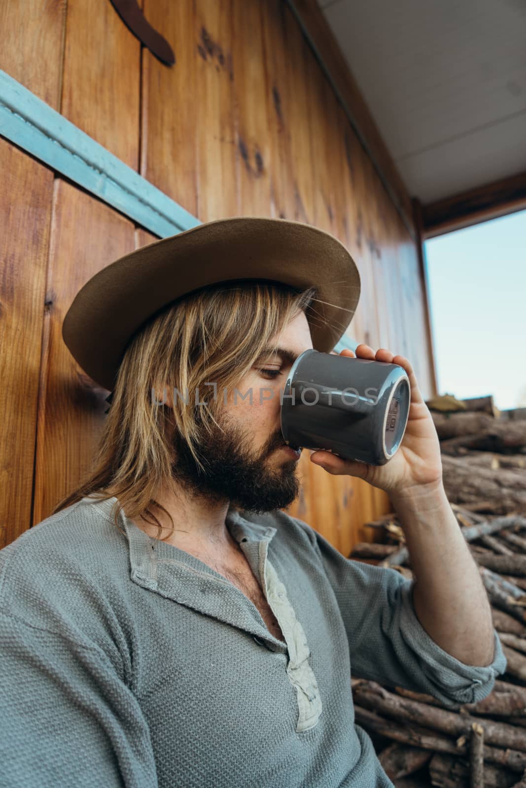 Young man with a beard drinking coffee on a wooden background