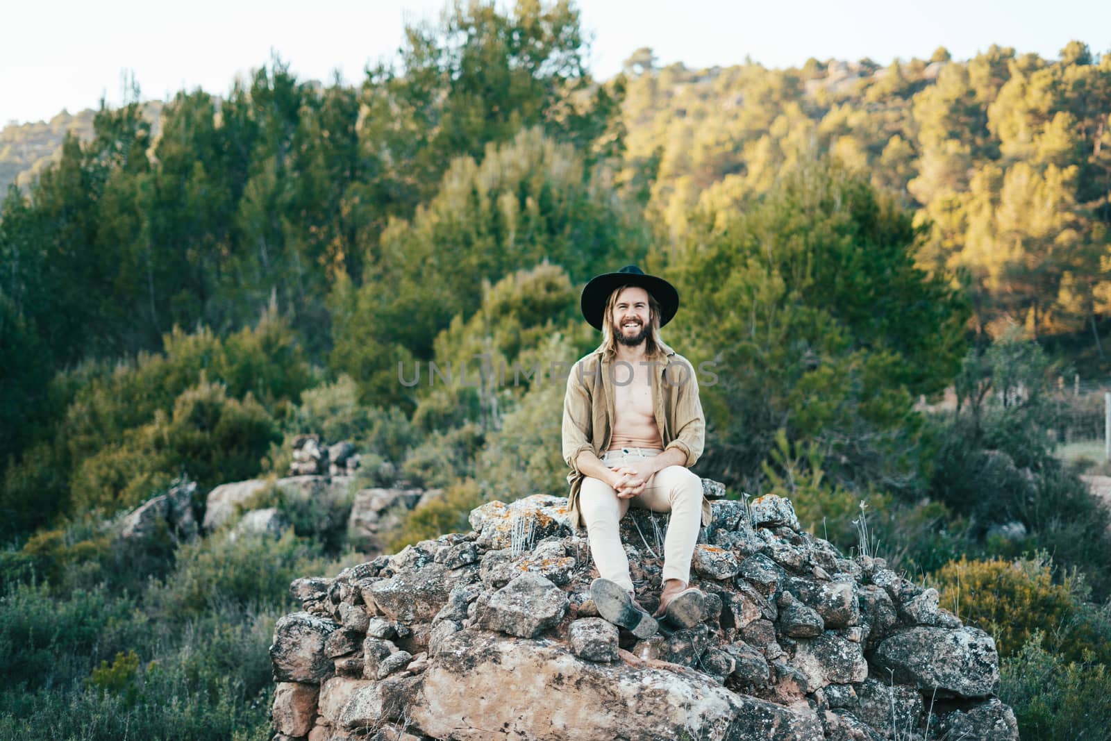 Young man with a beard and a hat on a beautiful sunset in the mountains
