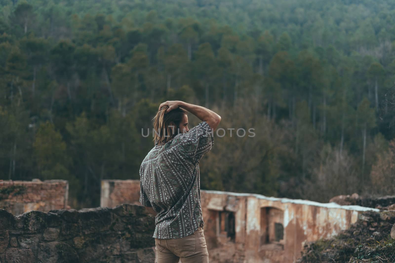 Bearded young man meditating in the middle of the mountain