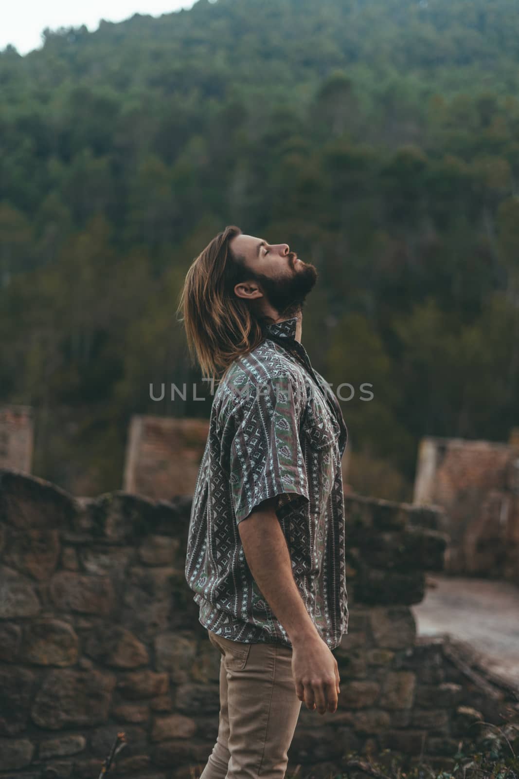 Bearded young man meditating in the middle of the mountain