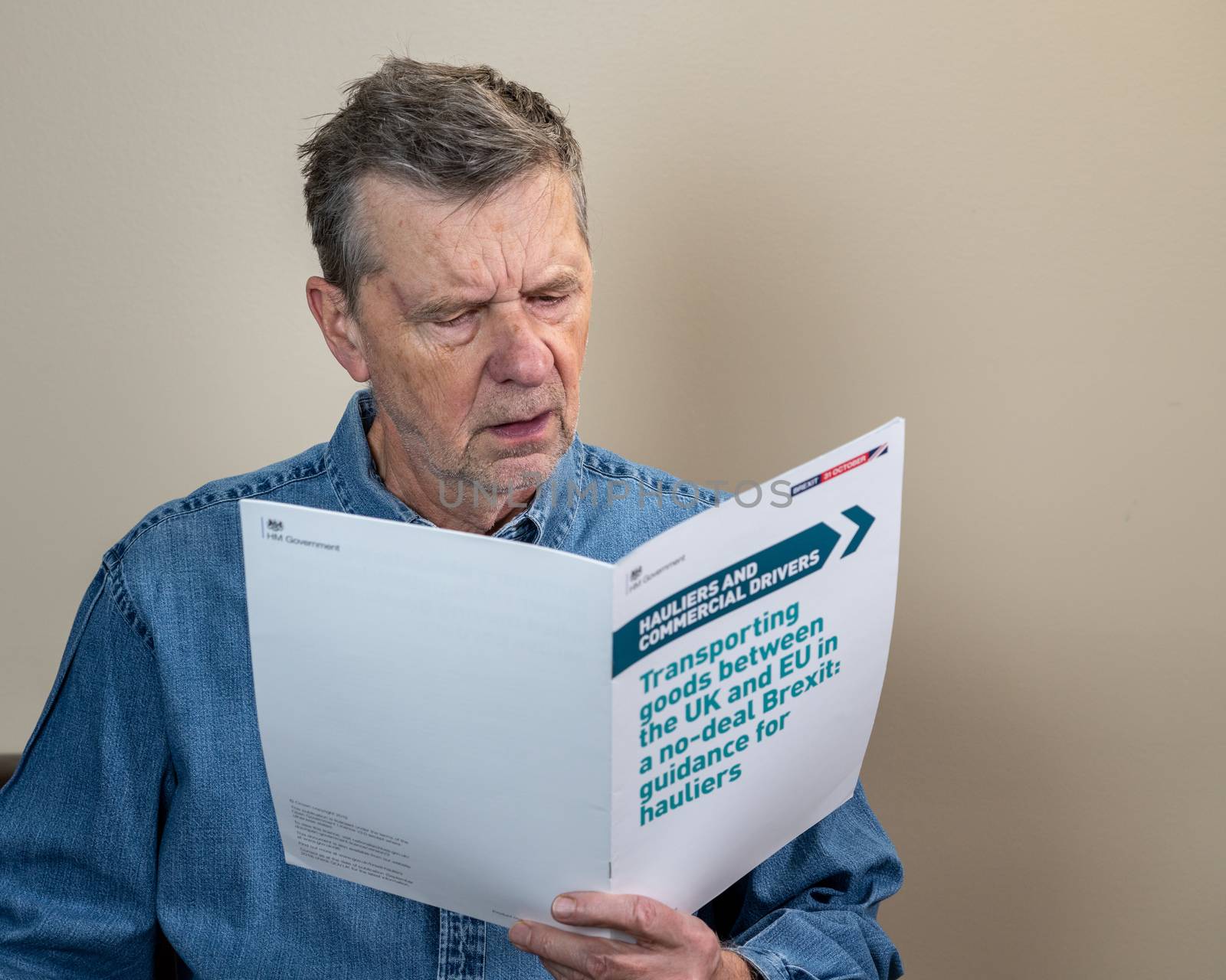 Senior caucasian truck driver reading Brexit no deal rules for exporting by steheap