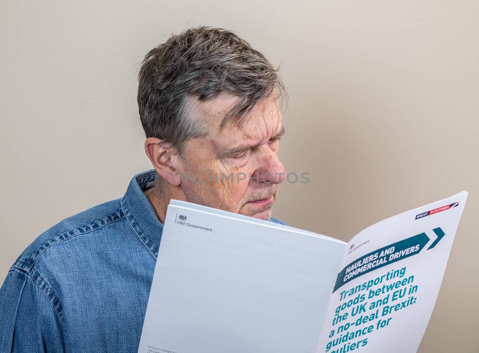 Worried senior man reading rules for transporting good to Europe in the event of no deal Brexit