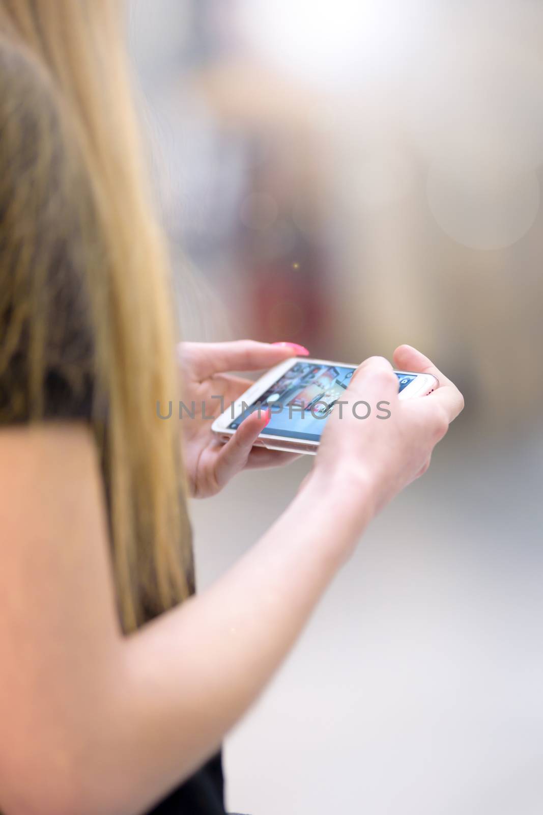 Young woman taking photo with her smartphone on the street.