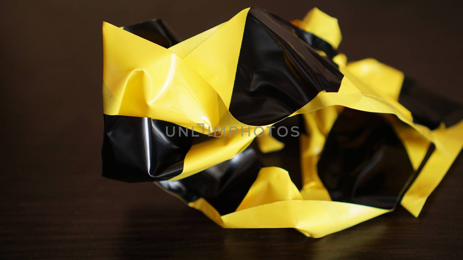 Crumpled yellow and black tape on dark background by natali_brill