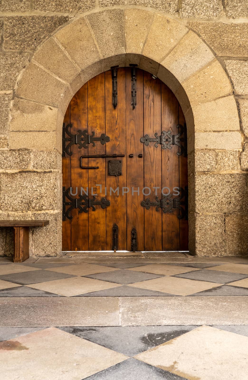 Solid wood and reinforced arched door inside historic monastery in Guimaraes