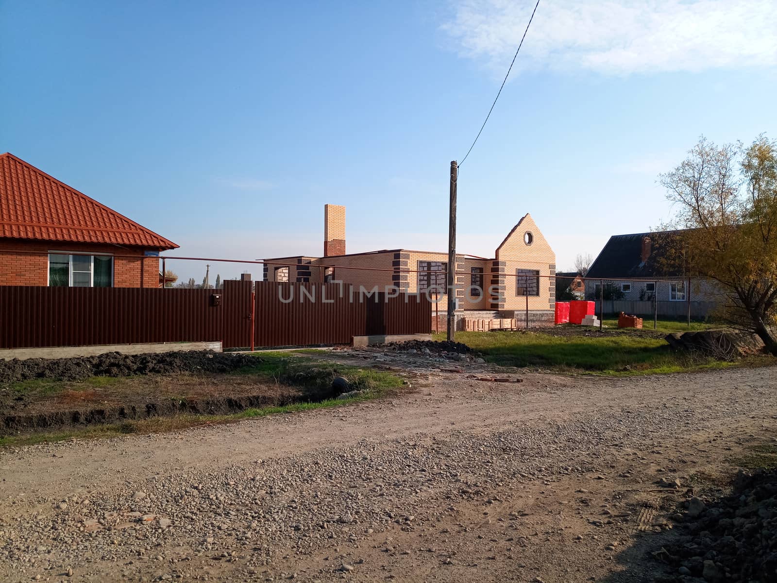 A new house with an orange roof and a brown fence.