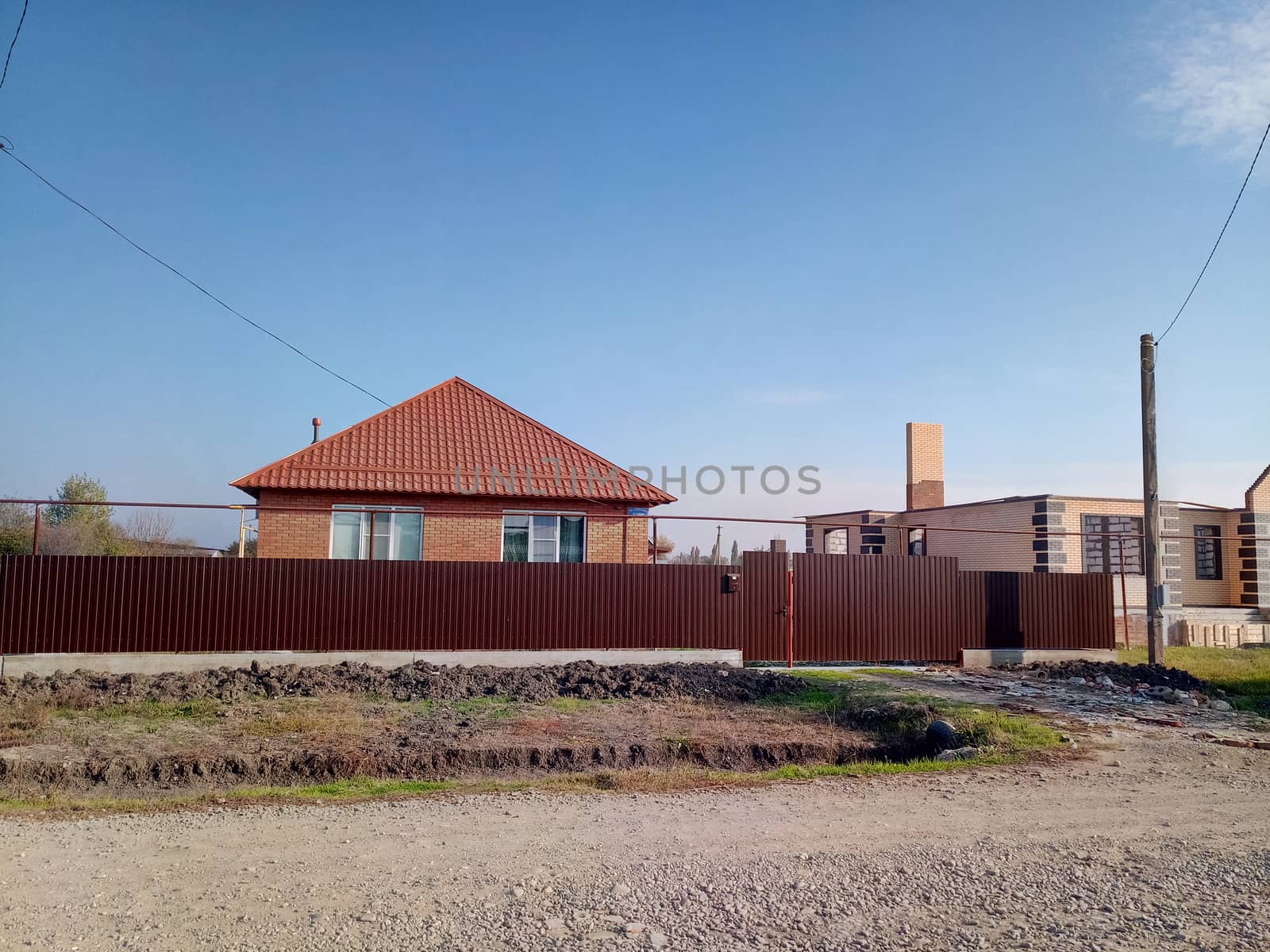 A new house with an orange roof and a brown fence.