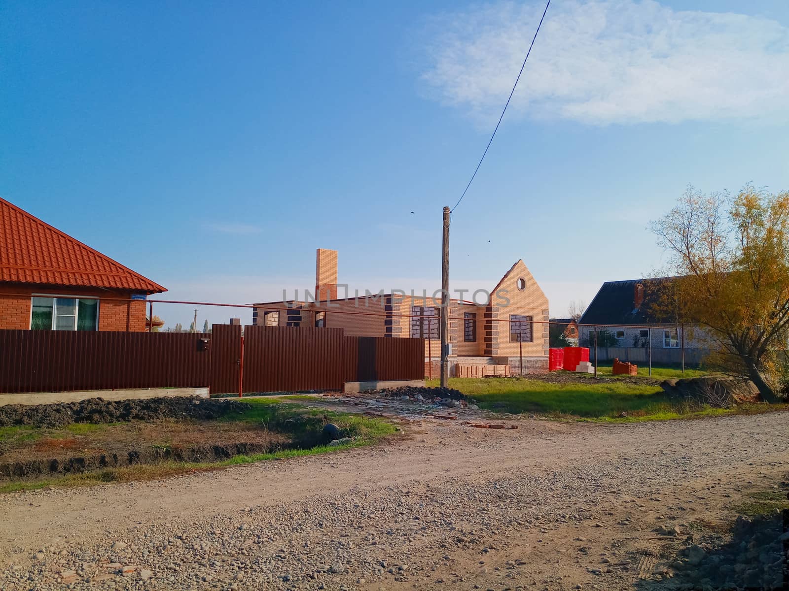 A new house with an orange roof and a brown fence.