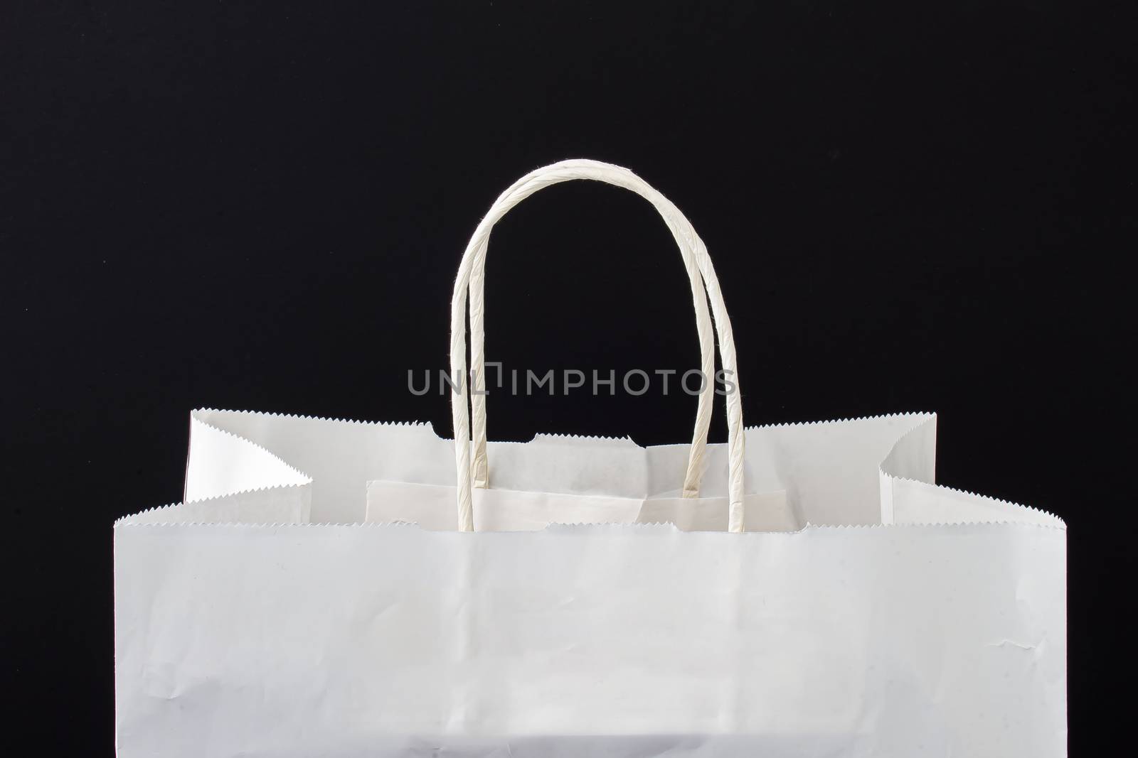 A white paper bag with holders on a black background by oasisamuel
