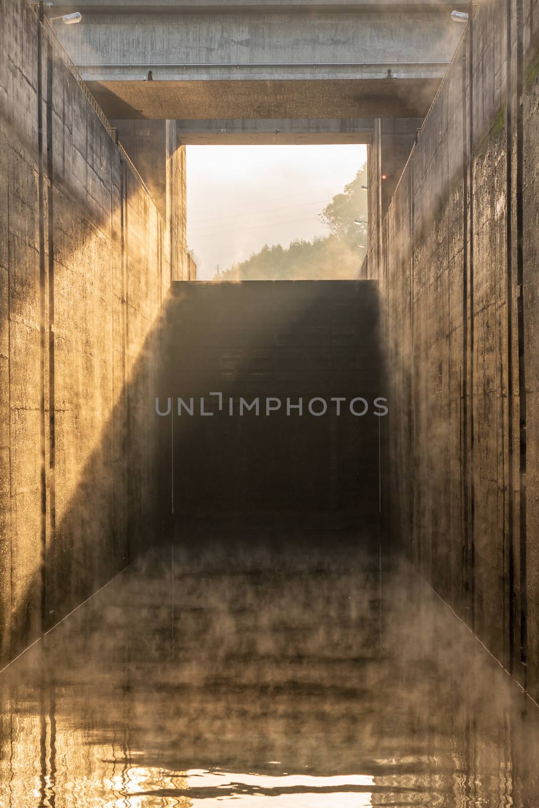 Calm water inside the concrete lock with the mist from sunrise at the Crestuma Lever dam on River Douro in Portugal