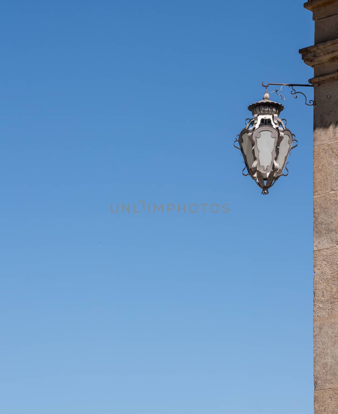 Detail of ornate lamp on side of building with blue sky by steheap