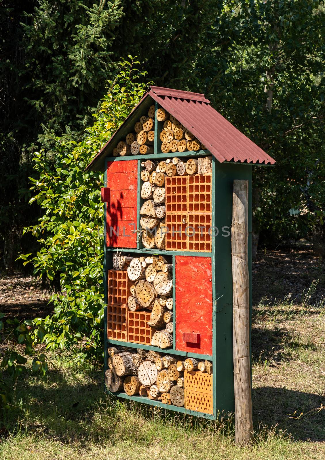 Construction for bird and insect hotel or home in garden with drilled tree trunks and branches