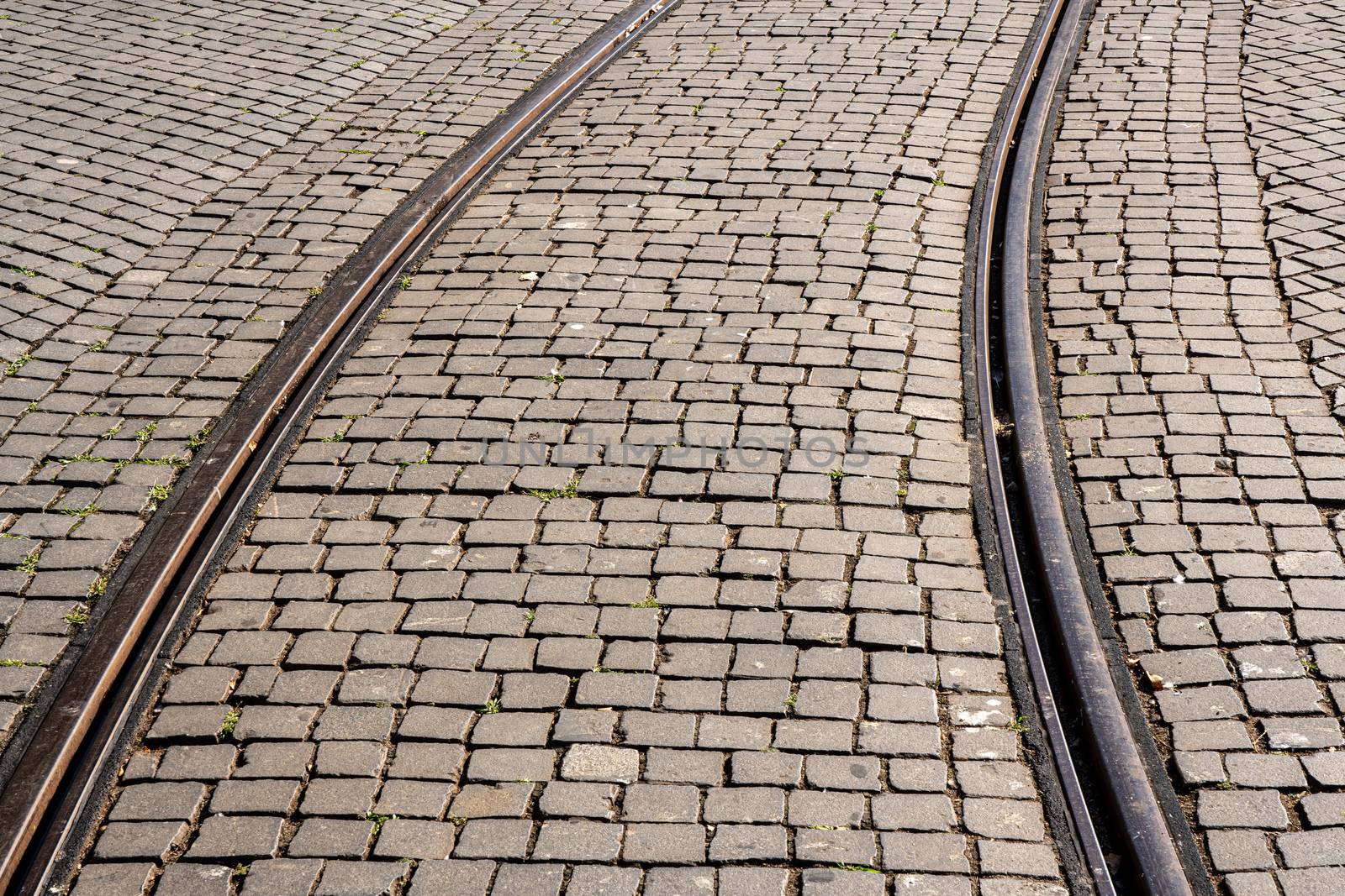 Curve of steel rails from tramcar track set into stone cobble pattern in Porto