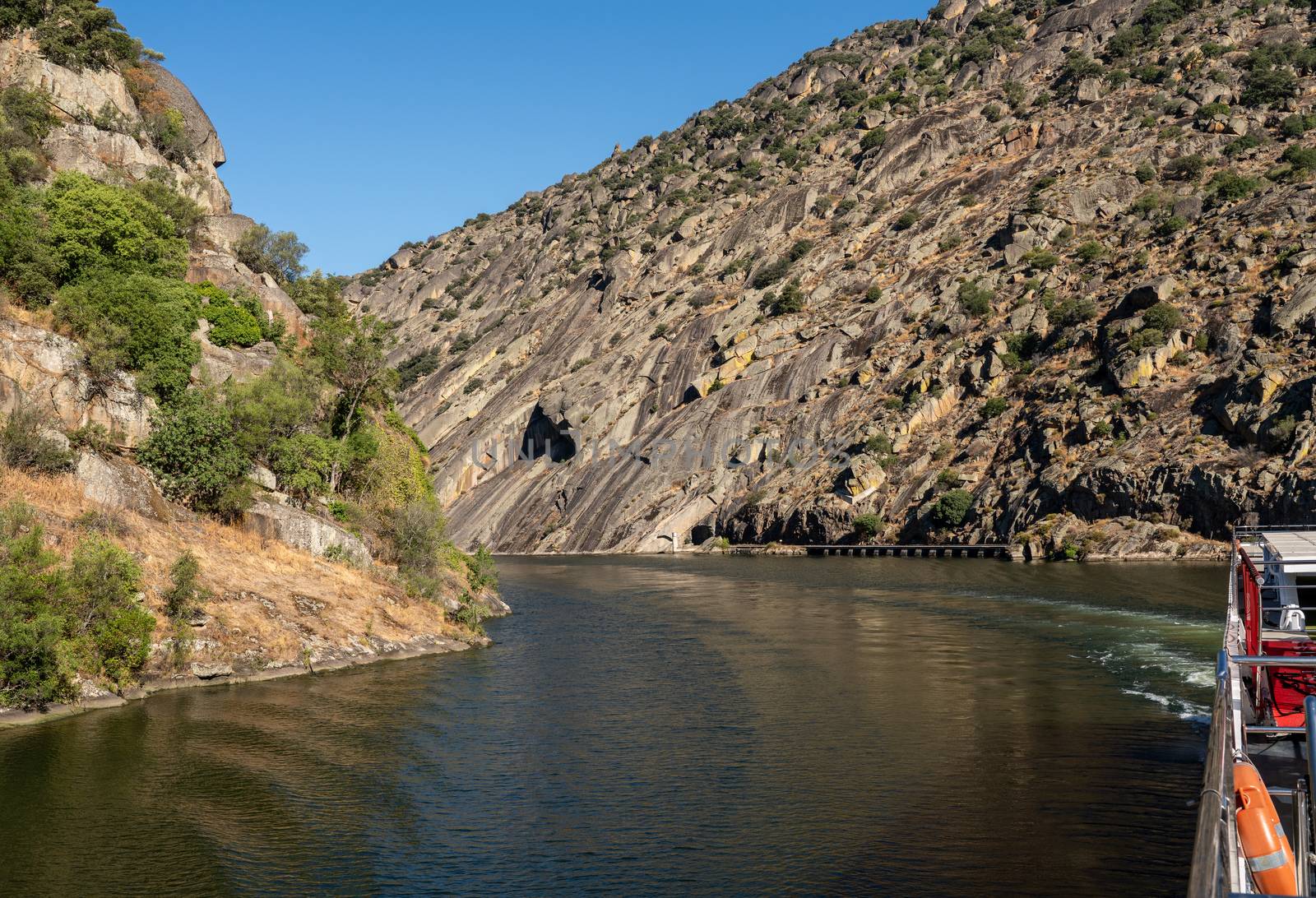 River boat cruising on Douro flowing through narrow rocky gorge in Portugal near Viseu