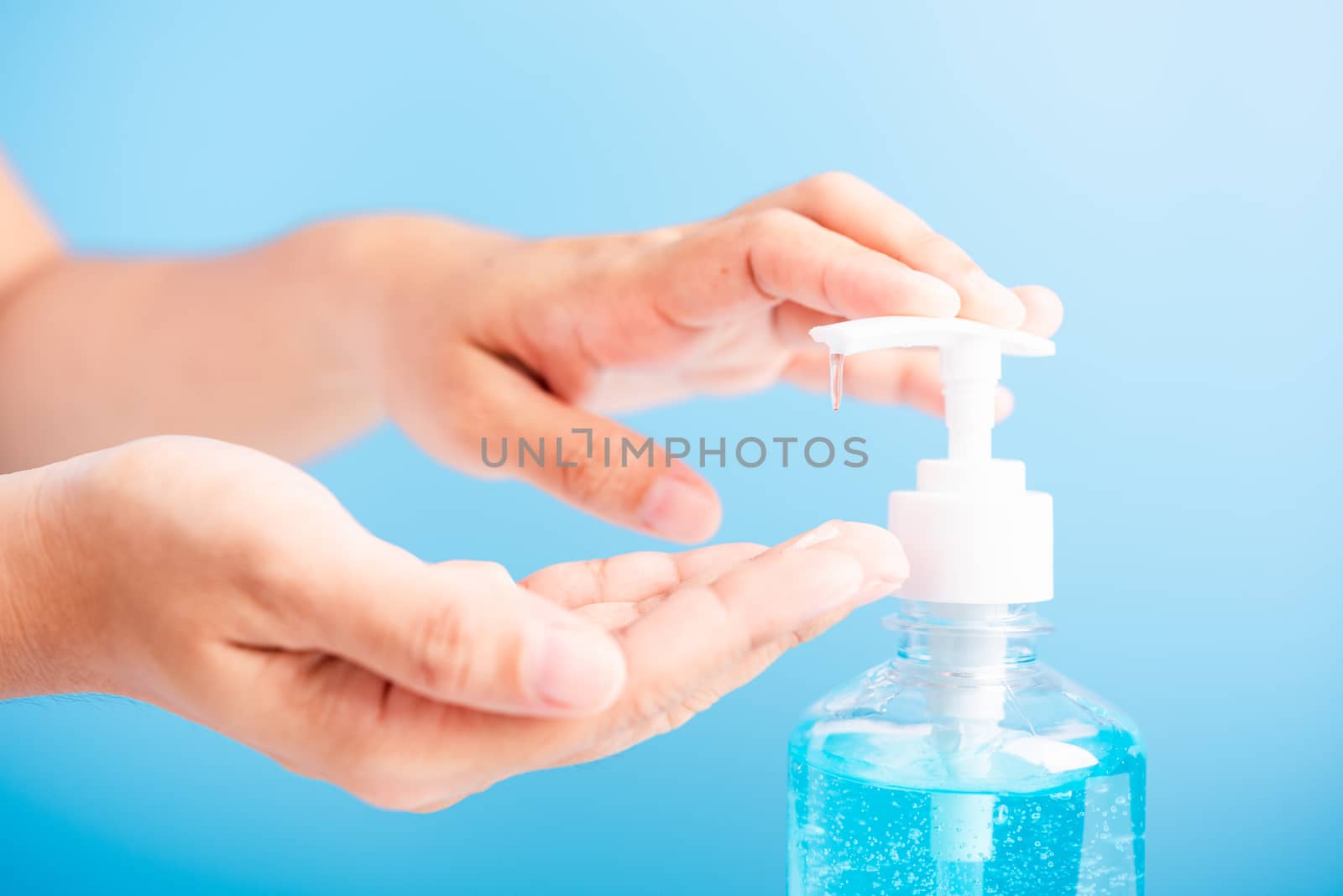 Close up Asian young woman applying press dispenser sanitizer alcohol gel pump to hand wash cleaning, hygiene prevention COVID-19 or coronavirus protection concept, isolated on blue background