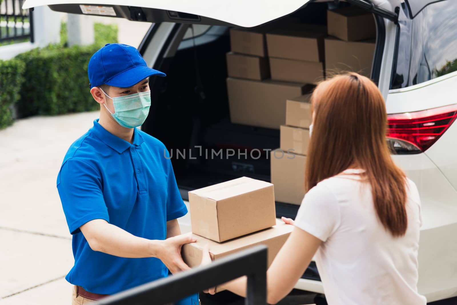 delivery man courier give parcel post box he protective face mas by Sorapop