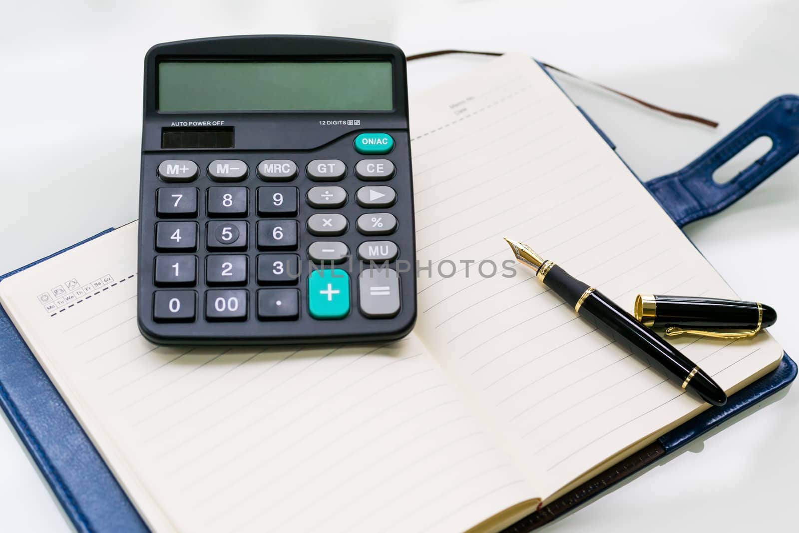 pen, calculator and notebook on the white table backgrounds