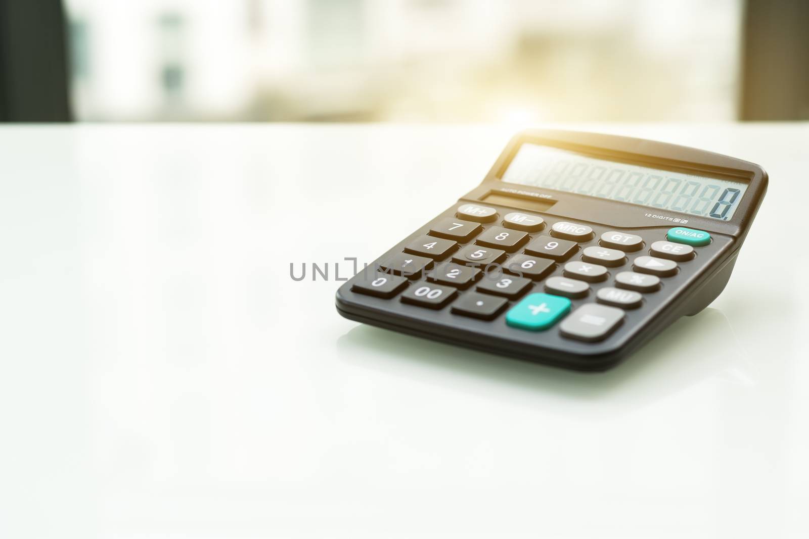 Calculator on the white table near window, sideview isolated with flare filter