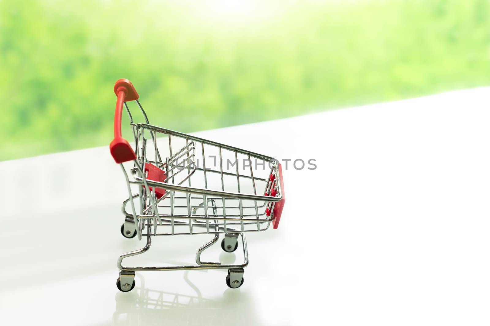 Empty shopping cart trolley on white table with green backgrounds