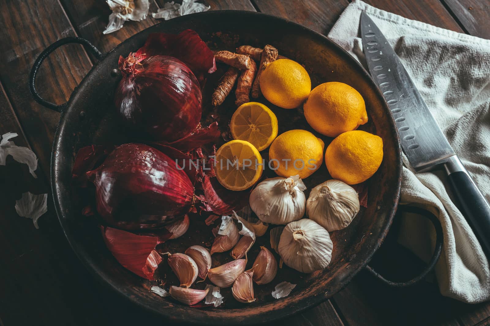 Paella with onion, turmeric, garlic and lemon on a wooden table with rustic tone and a knife