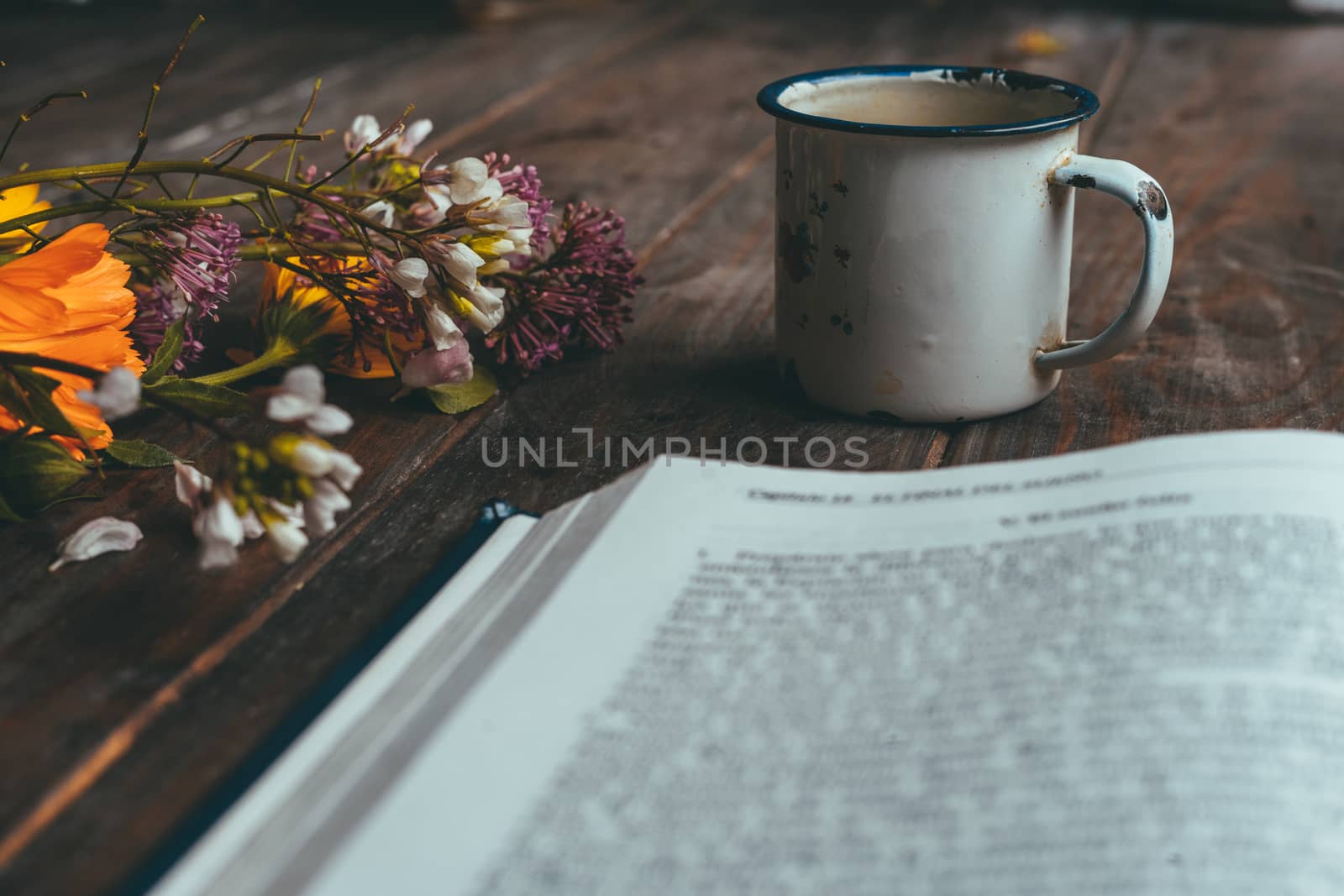 Book with spring flowers with a small white cup of coffee on a rustic wooden table