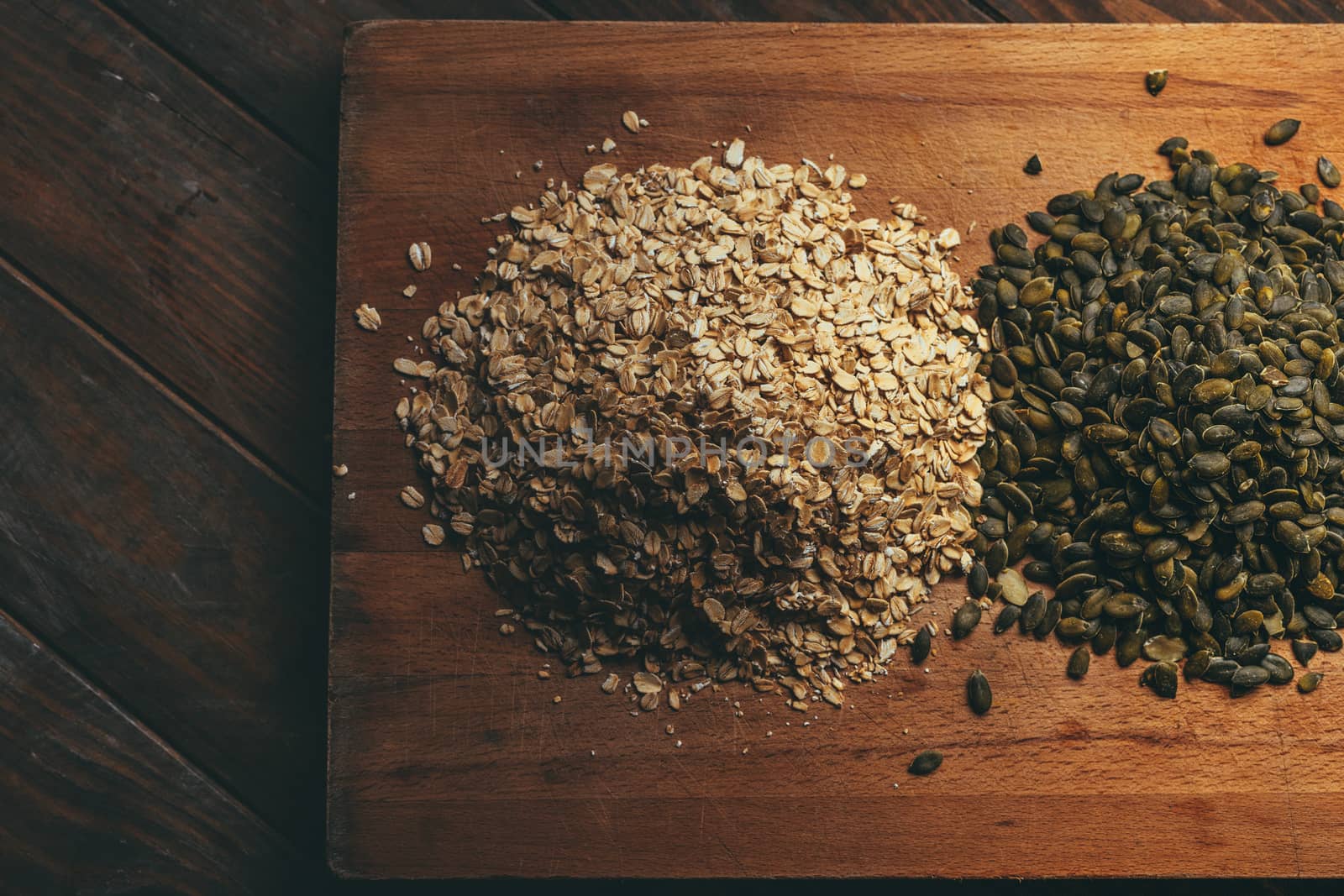 Oat flakes with pumpkin seeds on a wooden board on a rustic table