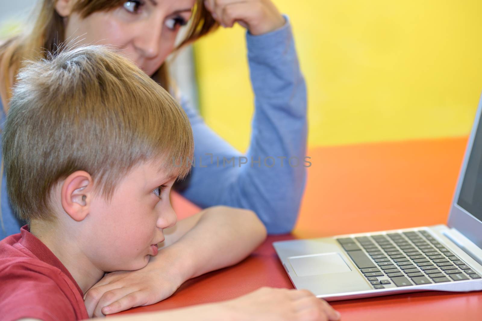 Boy works on a laptop with his mom by wdnet_studio