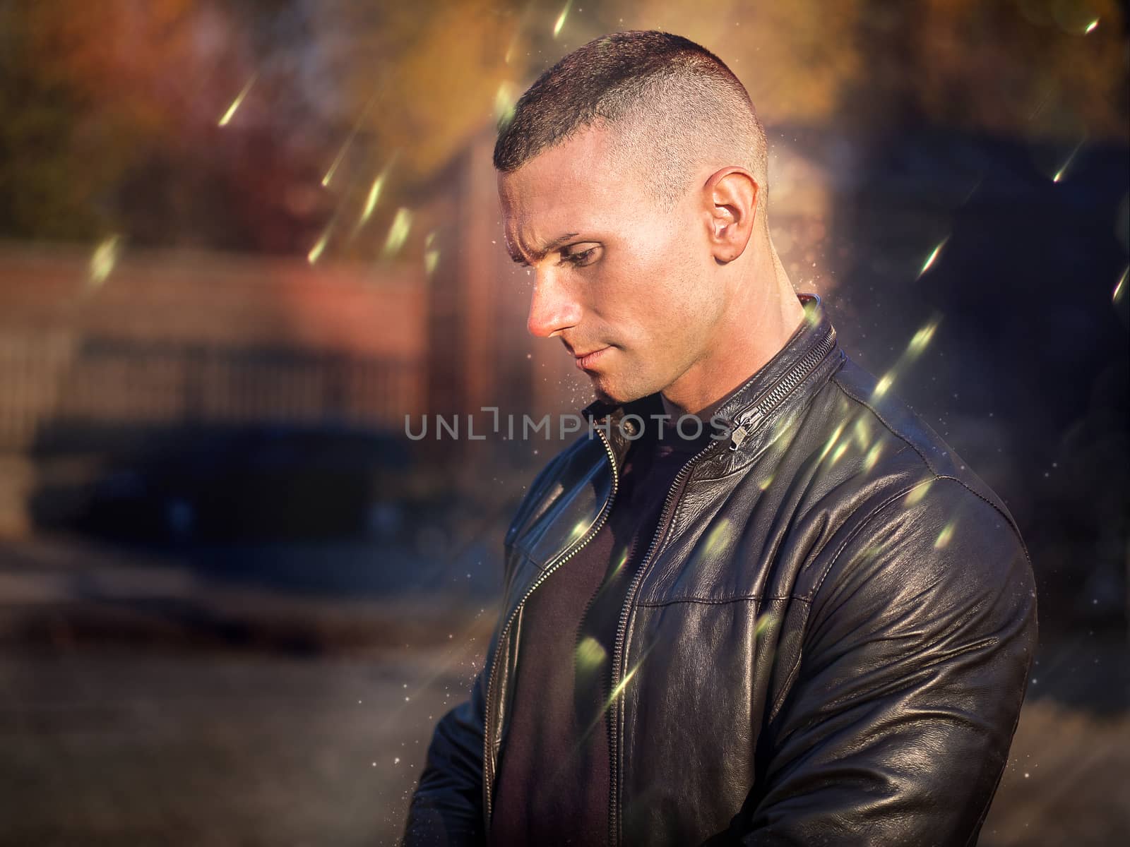 One handsome young man in urban setting in European city, standing, wearing black leather jacket and jeans