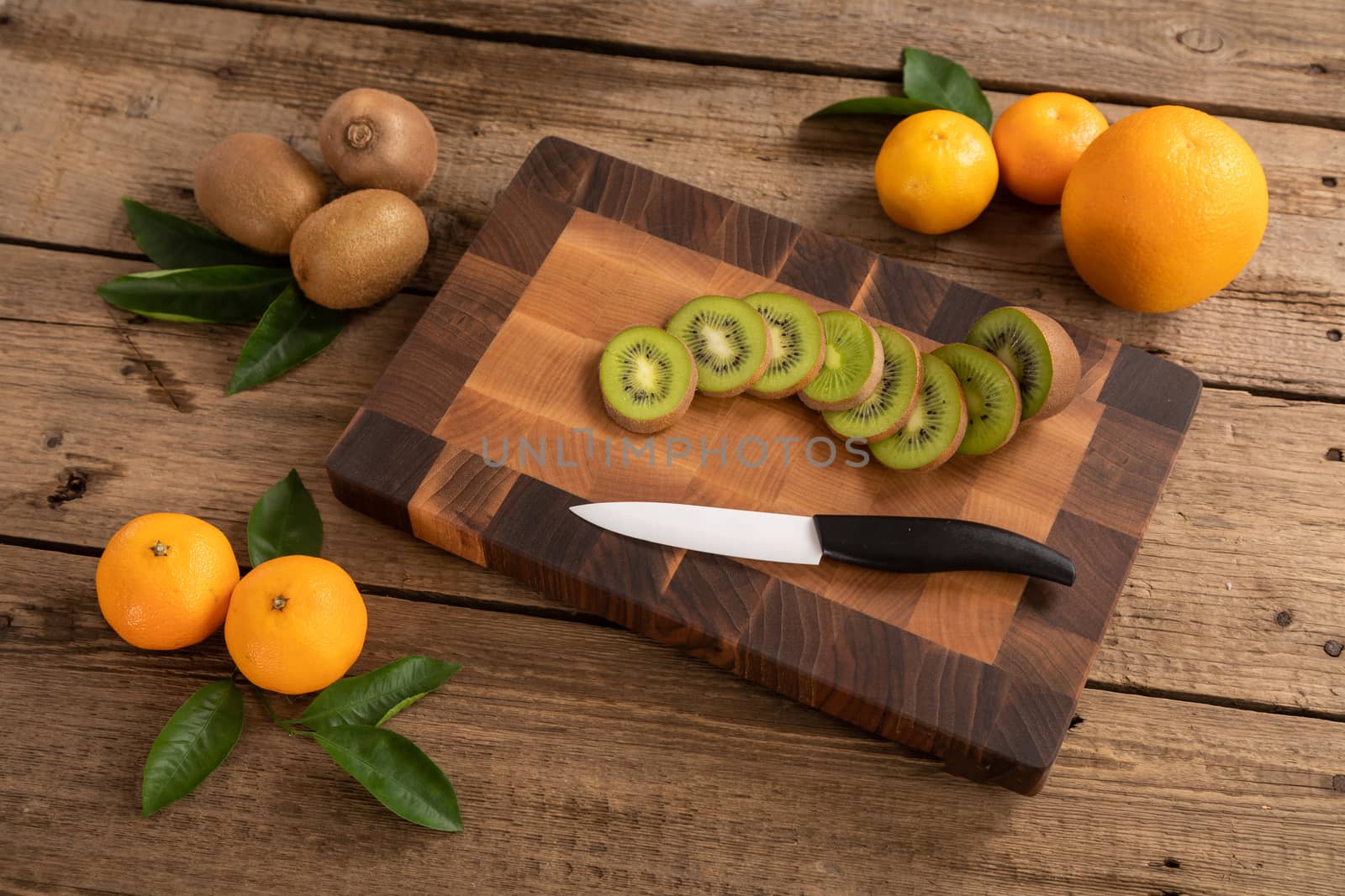 Juicy whole and sliced fruit with a knife on a wooden cutting board