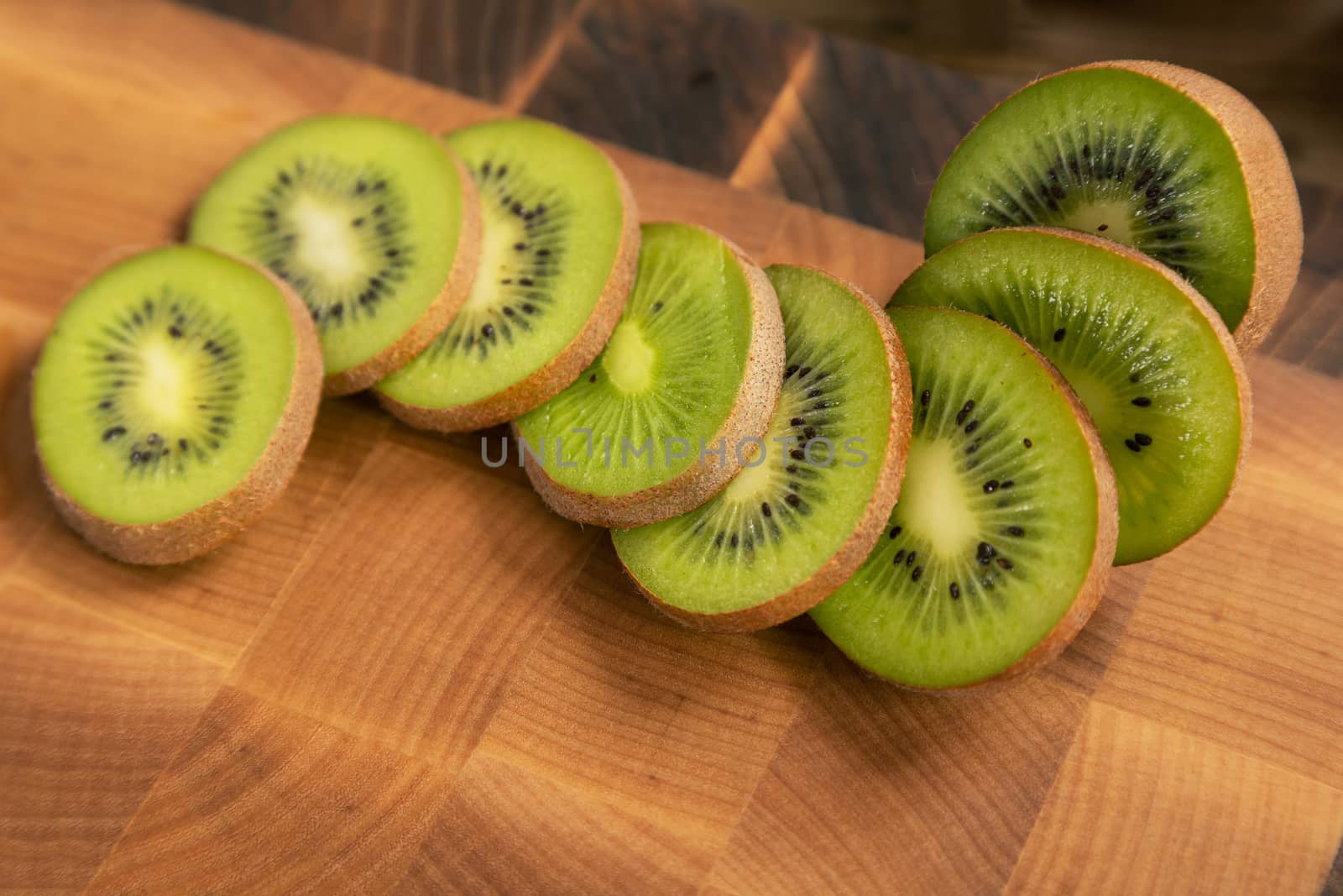 green kiwi sliced on wooden carving board by sveter