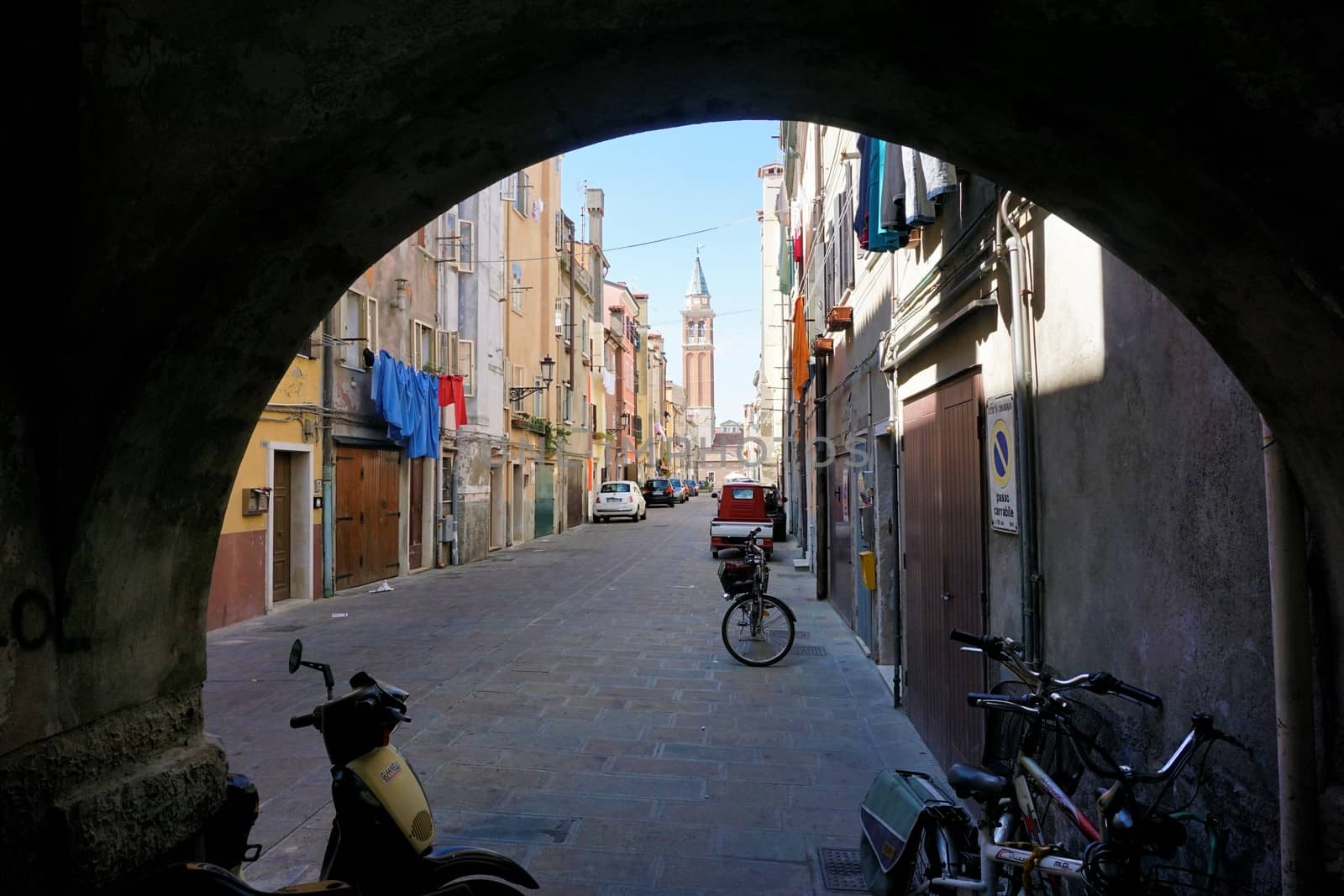 Typical street in the city center of Chioggia with bikes, scooters and cars by pisces2386