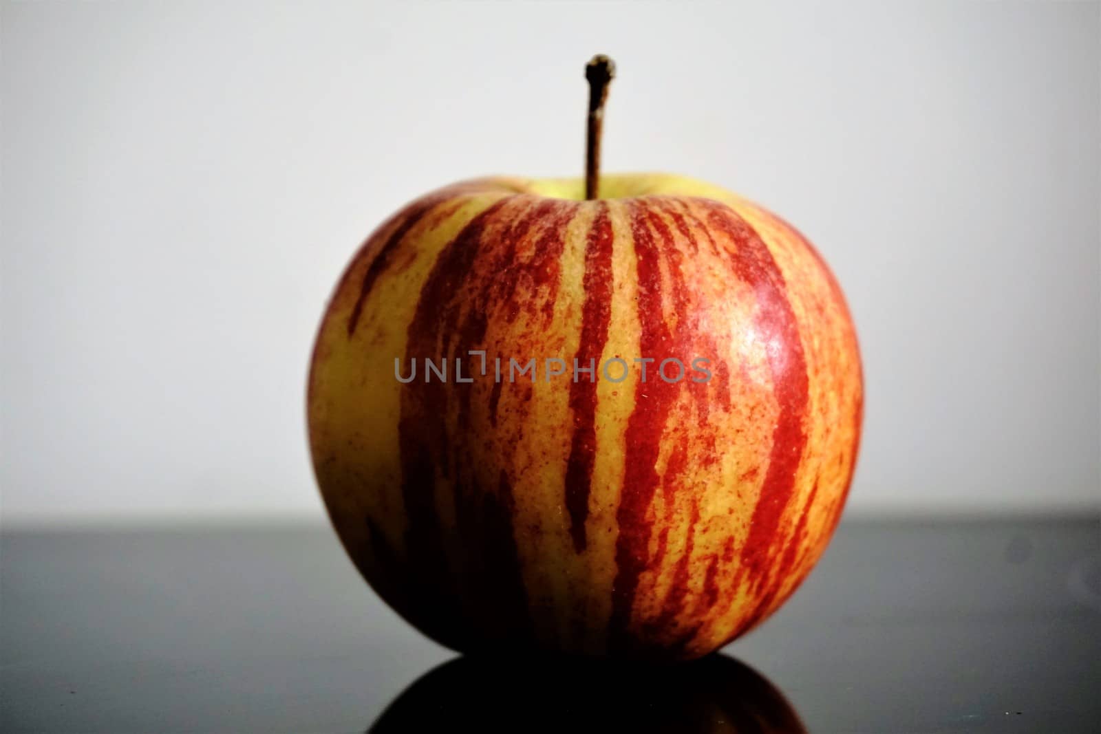 Photo of a single apple on a glass table