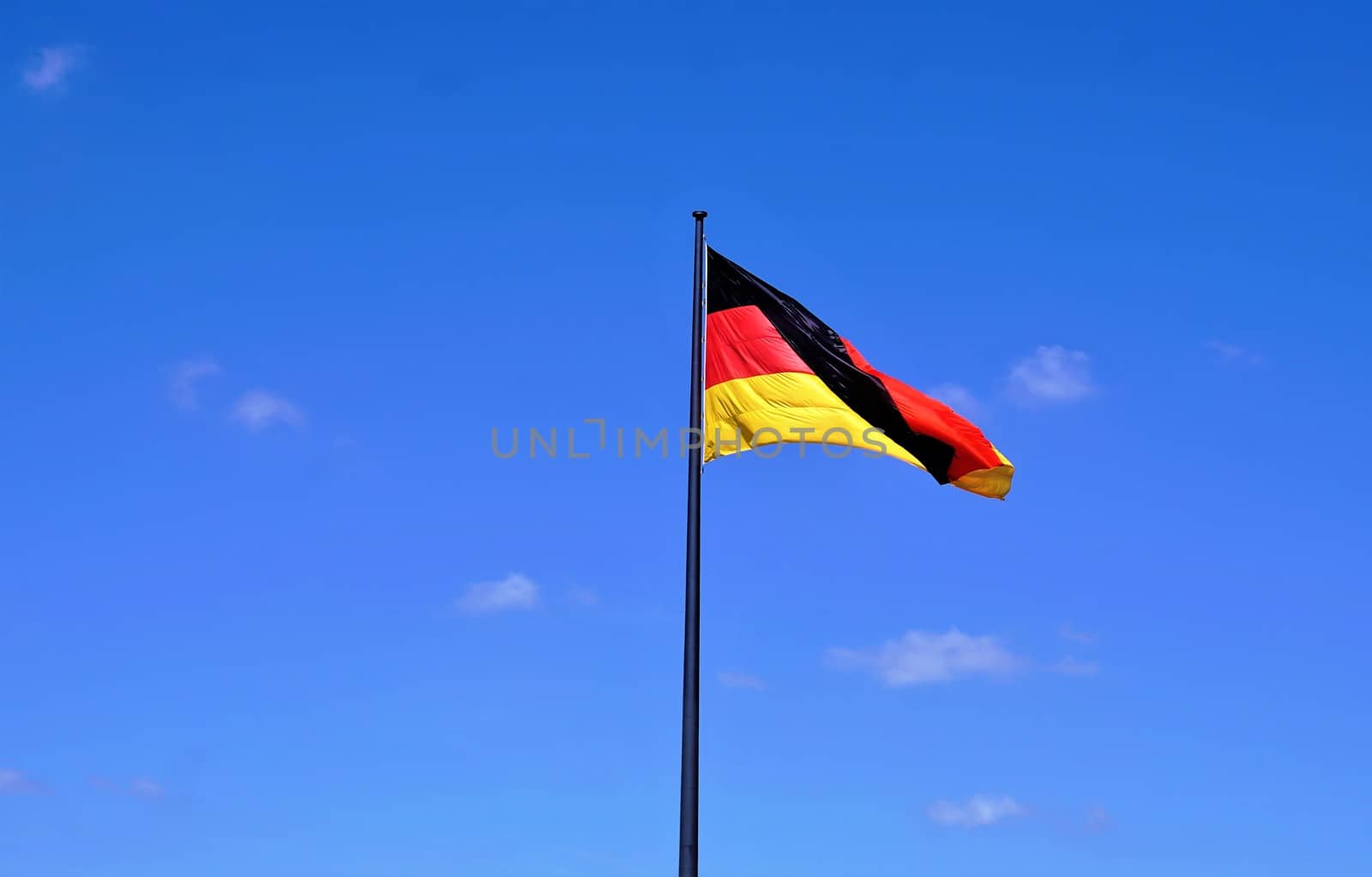 German flag waving in wind in front of blue sky