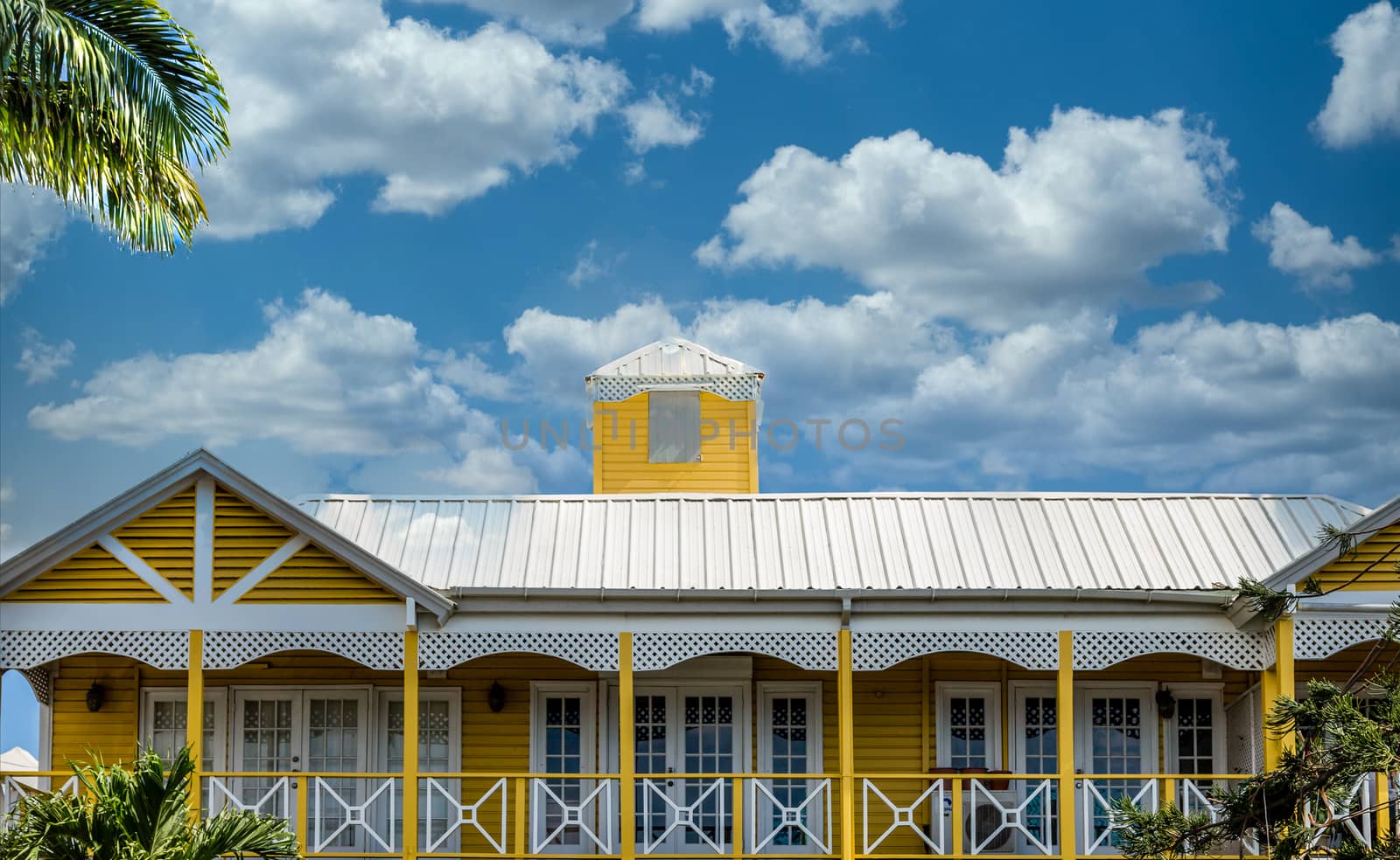 A large yellow tropical home under nice sky