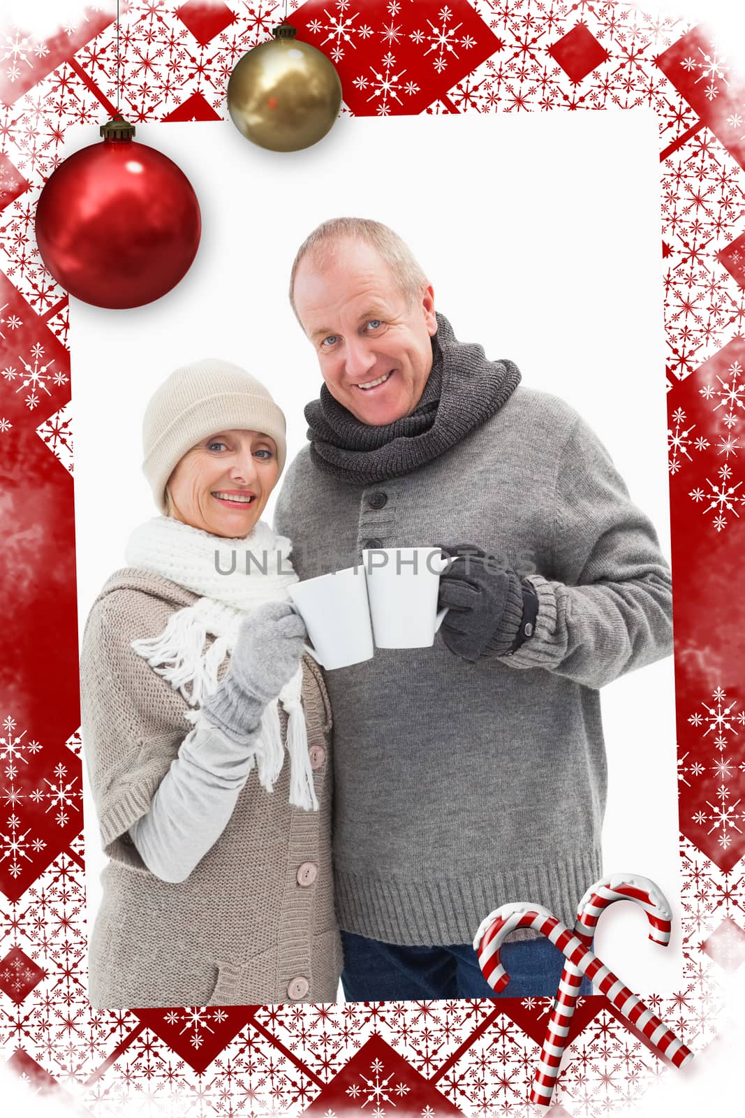 Happy mature couple in winter clothes holding mugs against christmas themed page