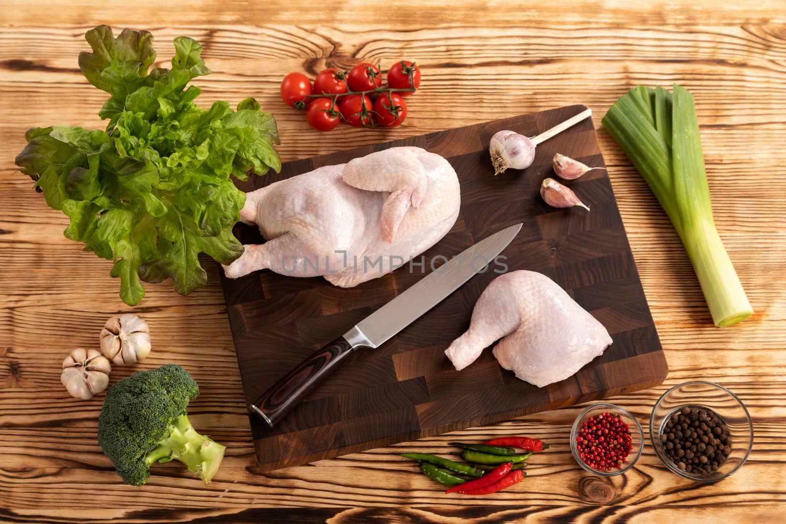 Raw chicken and vegetables on a wooden cutting board by sveter