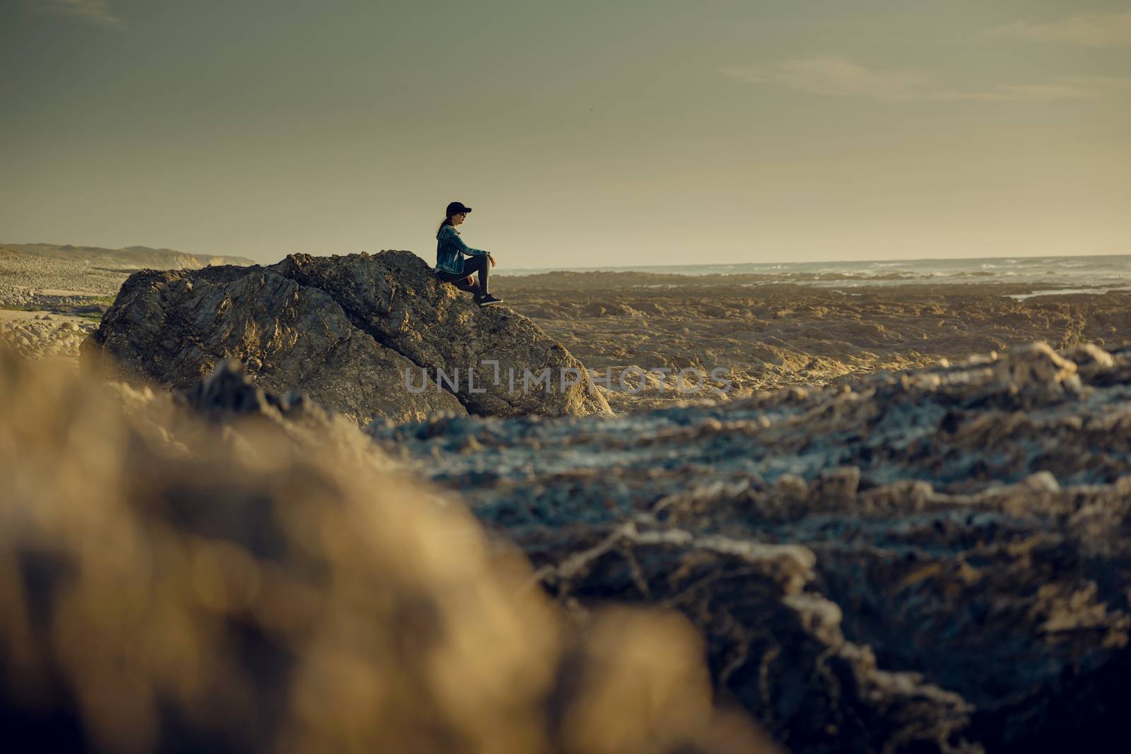 Beuutoful woman alone in the beach sitting on the rocks